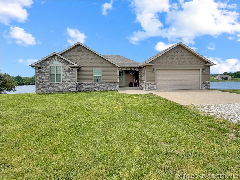 Experience lakefront living in this well-appointed 3-bedroom, 3-bath residence situated on a spacious waterfront lot with panoramic water and sunset views. Designed with comfort and entertaining in mind, the open-concept floor plan features abundant natural light, luxury vinyl plank wood flooring, concrete board siding, and a generously sized lower-level family room offering additional gathering space. The living room, kitchen, dining area, and primary suite all capture scenic lake views, creating a seamless connection to the surrounding landscape. Outdoor living is enhanced by a covered deck and lakeside patio, fire pit, and your own private sundock providing inviting spaces to relax, entertain, or enjoy the peaceful waterfront setting. Additional features include 12'+ ceilings, spa inspired primary suite, & $70K in updates, new HVAC, a 2-car attached garage on the main level along with a separate lower-level garage ideal for lake storage, workshop space, or recreational equipment. Conveniently located north of Warsaw with quick access to Highway 65, this property combines quality finishes, functional design, and a desirable lakefront location. Schedule your private tour today!