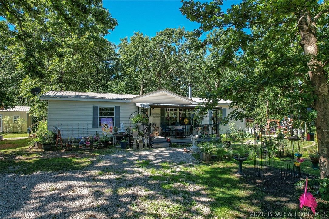 Tucked away at the end of a quiet dead-end road, this 8-acre property offers the peace, privacy, and space that's getting harder to find! Just minutes from Highway 7 and Lake of the Ozarks access, you'll enjoy a secluded setting without sacrificing convenience. The well-maintained 3-bedroom, 2-bath home features a spacious living room with a cozy wood-burning stove, an oversized kitchen with an island and lots of cabinet space, and a primary suite with a large walk-in closet, double vanities, soaking tub, and shower. The stunning timber-frame pavilion is a show stopper and perfect for gatherings or relaxing. A detached 30x40 insulated shop with concrete floors and electric is great for storage, workshop, and mancave and a 12x22 concrete pad with 30 amp hookup is just to the side. Plus, there is a heated/ cooled she-shed that would makes a great office or additional living space! The property offers mature landscaping, a large garden area, fenced backyard space, wooded acreage, and abundant wildlife. With NO hoa, there is flexibility for full-time living, long-term rental potential, or future development opportunities. Small town living in a great little community at the lake!
