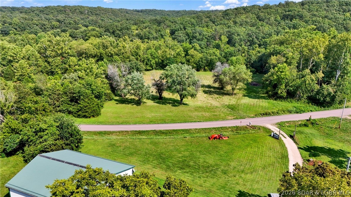 Cattle farm set up and waiting for you. 89.98 acres along blacktop highway not far from lake access, Versailles and Laurie. Nice country home complete with a beautiful view of the pond from the rear porch or all season room or screened porch. There are several outbuildings including a 1500 sq ft heated, cooled shop with elec and a bathroom and kitchen area. Enjoy your morning coffee on the front covered porch. There are 3 wells and 3 septics on the property. One exclusively for the shop. Shop has a 14ft door and fits a class C RV. Has its own 50 amp power hookup and dump station directly to the septic. Farm is set up for cattle but would be great for other livestock. Is fenced and has some cross fencing.