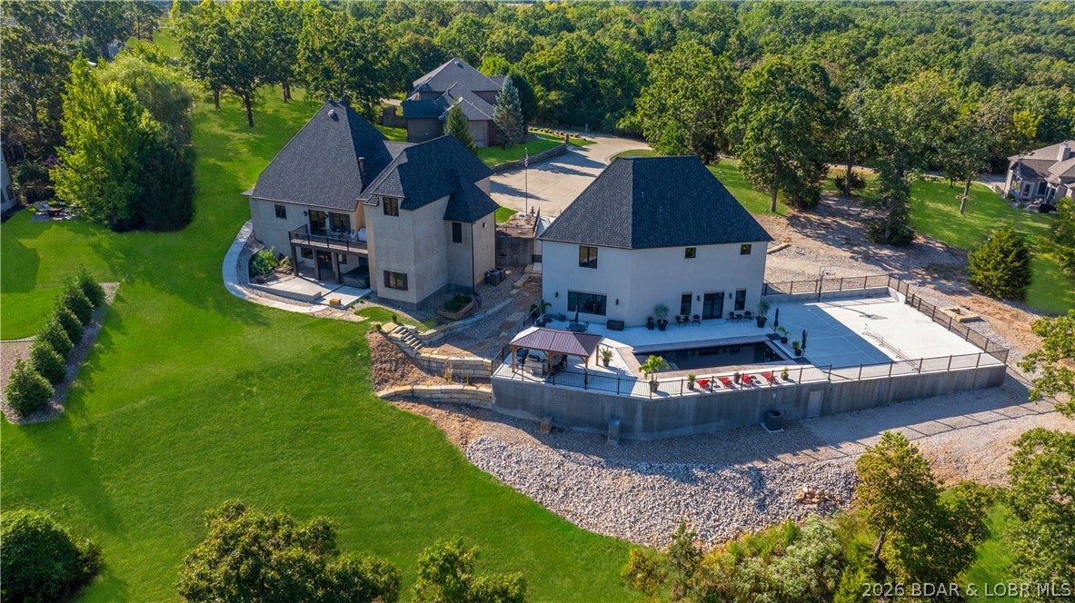 Welcome to a one-of-a-kind luxury estate in a gated Osage Beach community, occupying the feeling of its own private cul-de-sac. This entertainer's dream includes a 12x30 ft boat slip + PWC slip at the community dock, oversized 6+ car garages, a private pool, covered outdoor kitchen, private pickleball court, and half basketball court. The private pool house features its own kitchen, tons of entertainment space, an 8th bedroom currently used as a gym, sauna, and 2 bathrooms. The 7-bedroom main home offers 4 full & 2 half baths. High-end finishes include Travertine floors, wood beams, hardwoods, tall windows, vaulted ceilings, 8' doors, Alder millwork, and a stunning 3-story stairway. The expansive master suite boasts a fireplace, stone shower, soaking tub, dual sinks, and custom built-ins. The custom-designed kitchen features a high-end gas range, abundant handcrafted cabinetry, and a spacious walk-in pantry—perfectly blending style and function. The lower-level bar is a showstopper with stone seating and a cedar wine/bourbon locker. This home is loaded with custom; luxury details you must see to believe!