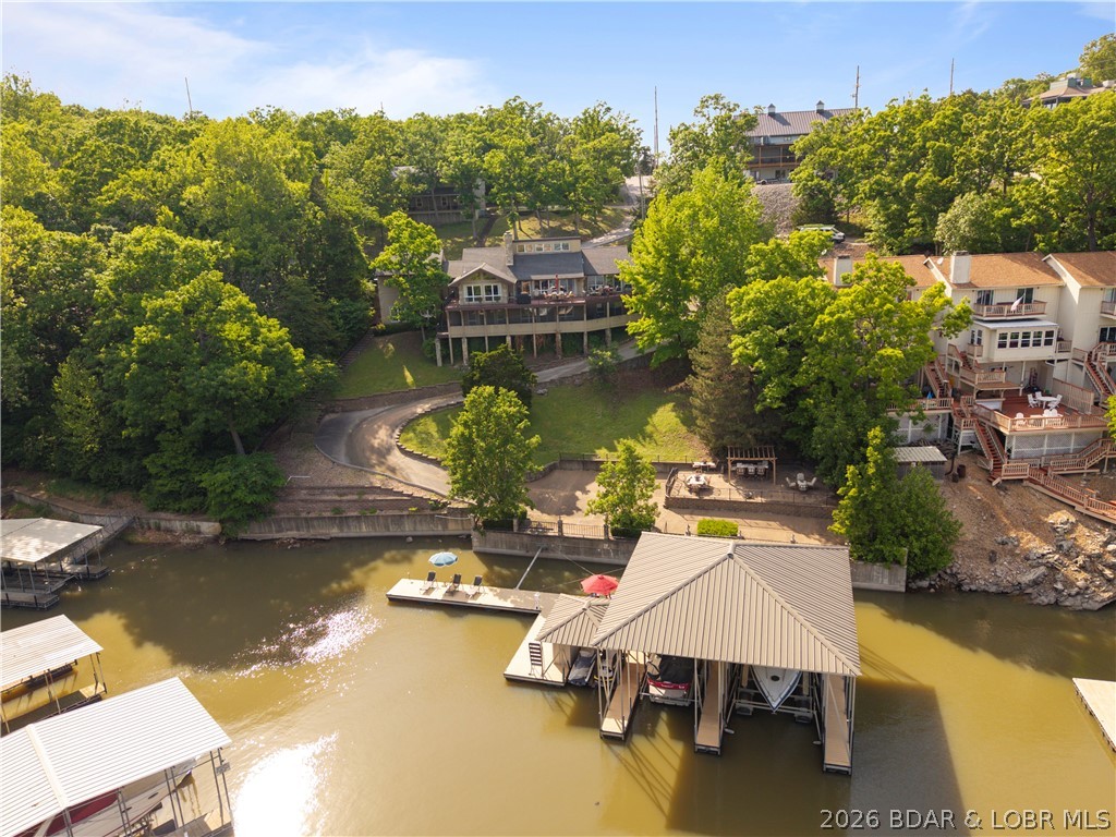 Experience true Lake of the Ozarks living at this exceptional waterfront retreat where every detail is designed for relaxation, entertaining, and effortless lake life. From the moment you step onto the property, it instantly feels like home with its inviting atmosphere, prime lakefront location, and spaces designed to bring people together. The massive entertainer’s dock is the showpiece of the property, featuring a large swim platform perfect for soaking up the sun and enjoying long summer days on the water. Boaters will appreciate the cruiser slip, while the tiki bar creates the ultimate gathering spot for sunset cocktails, weekend entertaining, and unforgettable evenings at the lake. The lakeside patio offers a peaceful setting for morning coffee, outdoor dining, or unwinding after a day on the water with panoramic lake views all around. A paved drive extends directly to the dock, providing easy access and adding to the convenience of everyday lake living. Whether you’re searching for a full-time residence, weekend escape, or investment opportunity, this prime waterfront property delivers the perfect blend of comfort, fun, and effortless lakeside living.