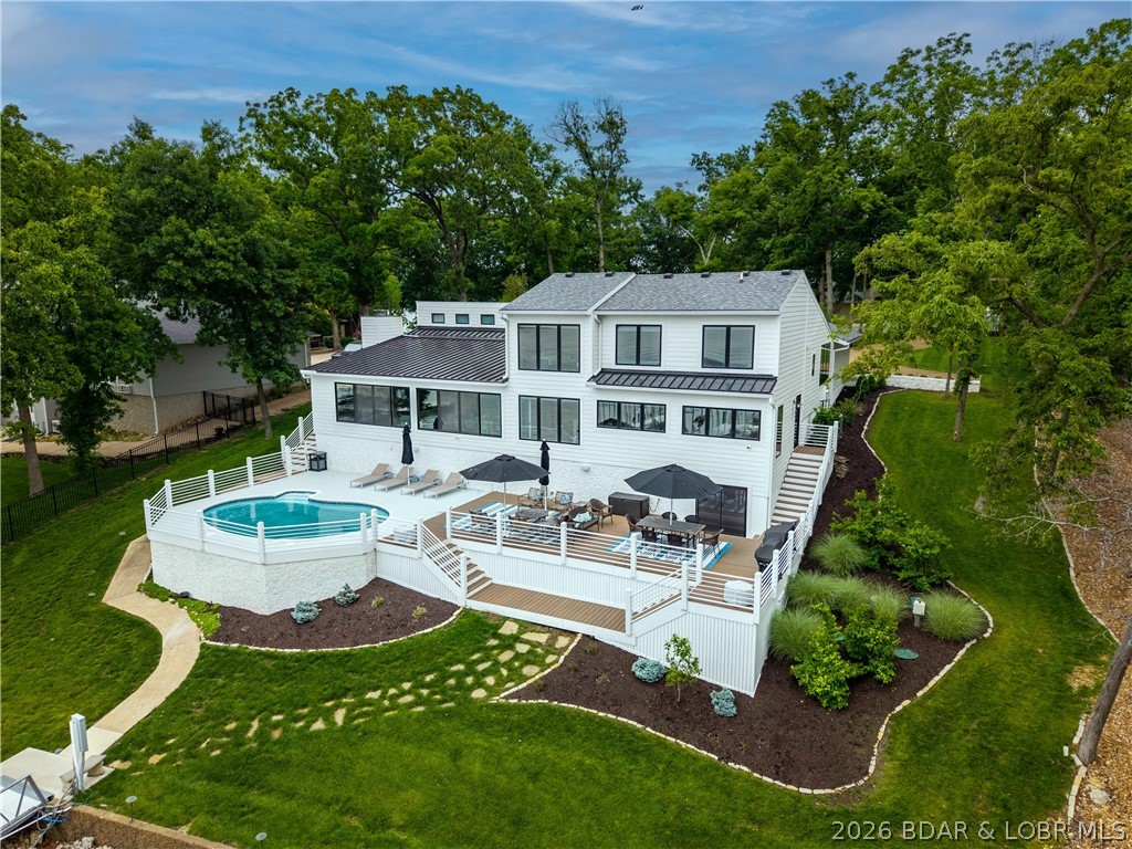 This home offers only the finest finishes, located in coveted 6 Mile Cove,the only non-mooring cove at Lake. Blending charm, character, & elegance, this exceptional property on Belle Vista Ct delivers the ultimate lakefront lifestyle.Situated on an extremely level & gentle lot, it offers a cove setting w/ stunning main channel views. It features 5 bedrooms plus an office, including a luxurious primary suite w/ a spa-inspired bath. Open-concept great room showcases detailed ceilings, gathering area w/ Fireplace & an additional seating space. The chef’s kitchen is designed to impress, featuring a large bar area, walk-in pantry, coffee bar, premium cabinetry, & high-end appliances. Exceptional lighting & designer finishes are showcased throughout. Spacious four-seasons room captures breathtaking lake view, while an additional upstairs sitting/TV room provides extra space for relaxation. Modern automation enhances the property. The grounds include an in-ground swimming pool & private pool bath. The dock is one of a kind at the lake,offering two 16x46 slips w/ room to add a 3rd slip,full bar area, & four PWC spaces. The home may also be offered furnished, including décor & accessories.