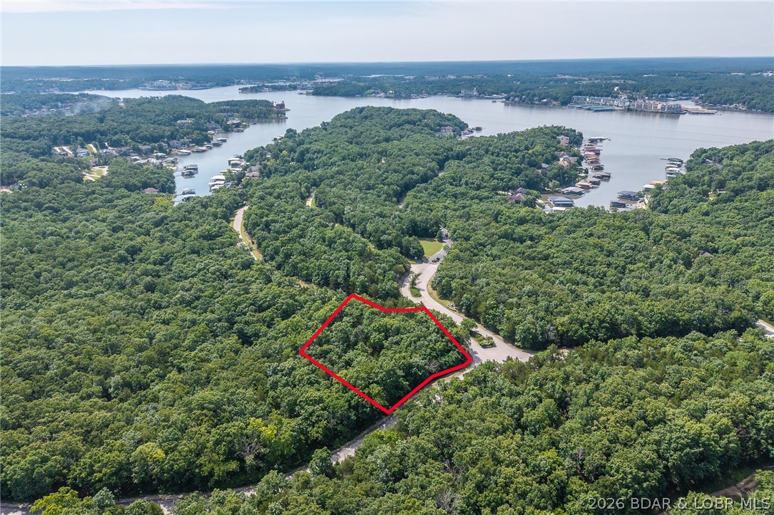 Surrounded by mature trees and natural Ozarks beauty, this wooded lot at The Villages at Shawnee Bend offers a peaceful, private setting within one of Lake of the Ozarks’ most distinguished communities. From the moment you arrive through the grand waterfall entrance, the neighborhood’s upscale character is clear. Residents enjoy access to a beautifully appointed clubhouse, resort-style community pools, championship tennis courts, and pickleball facilities, along with parks, playgrounds, and marina access. Paved roads and underground utilities make building seamless while preserving the natural landscape. Ideal for a custom home or lake retreat, this wooded homesite blends serenity, luxury, and an active lake lifestyle.