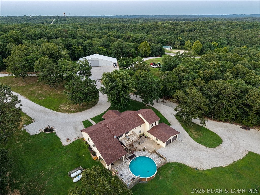 No you're not dreaming...this one of a kind property has it all! You don't need to travel for your vacation just shut off the technology & step outside. Updated home sits on 71+ beautifully manicured acres & has a 48x98 shop & an incredible former quarry. The upper level of the quarry includes an established shooting range while the lower quarry is filled with clear water & stocked with crappie, bass & bluegill. Enjoy a picnic area, park like grounds & graveled paths throughout. Live, hunt, fish, swim, target shoot & potentially operate a business all with highway frontage just 1 minute from Versailles & 8 minutes to the Gravois Mills boat launch to Lake of the Ozarks. The updated 4 bedroom home features an open kitchen, dining & living area designed for entertaining, with easy access to the upper deck and covered front porch. The primary suite has walls of windows bringing the outdoors inside, while also offering a sitting area, 2 closets, garden tub & separate shower in the bath. Downstairs, the bar and family room are open to the lower deck, patio & pool. An outdoor covered game & BBQ area with soaring ceilings and fans provides the perfect place to relax. You must see this one!