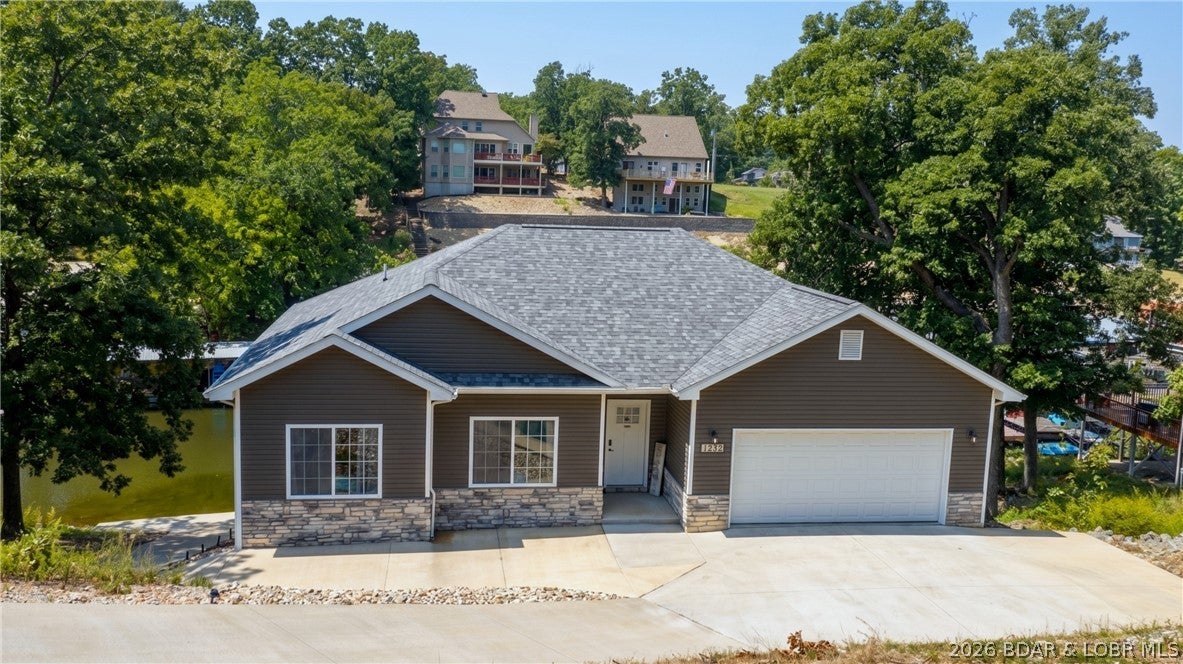 IMPRESSIVE Lake home built in 2022 with a perfect floor plan! Step inside to a gorgeous open great room with 12-foot coffered ceilings, walls of windows, electric fireplace, easy-care LVP flooring, spacious kitchen & dining areas. Relax lakeside on 2 decks with main channel views. The kitchen features SS appliances & granite countertops. Lakeside primary suite offers a private bath, walk-in shower & walk-in closet. Main level also includes 2 guest bedrooms, full bath & laundry. Lower level presents a large family room, guest bedroom, full bath, laundry & additional 500+ sq. ft. ready for your imagination—storage, bedrooms, theater room or more! Covered/open lower deck, plus a hot tub for relaxing after a day on the lake. Few, easy steps to the dock, with cart path access from the driveway. Protected cove with good water depth. Enjoy swimming, kayaking, fishing, paddle boarding from the concrete dock on weekends & holidays. Extra lot provides extended privacy. Conveniently located in town with city water & sewer and no HOA, short-term rentals allowed! Close to all the best attractions at the 18MM! Enjoy this dream home and/or add it to your investment portfolio!