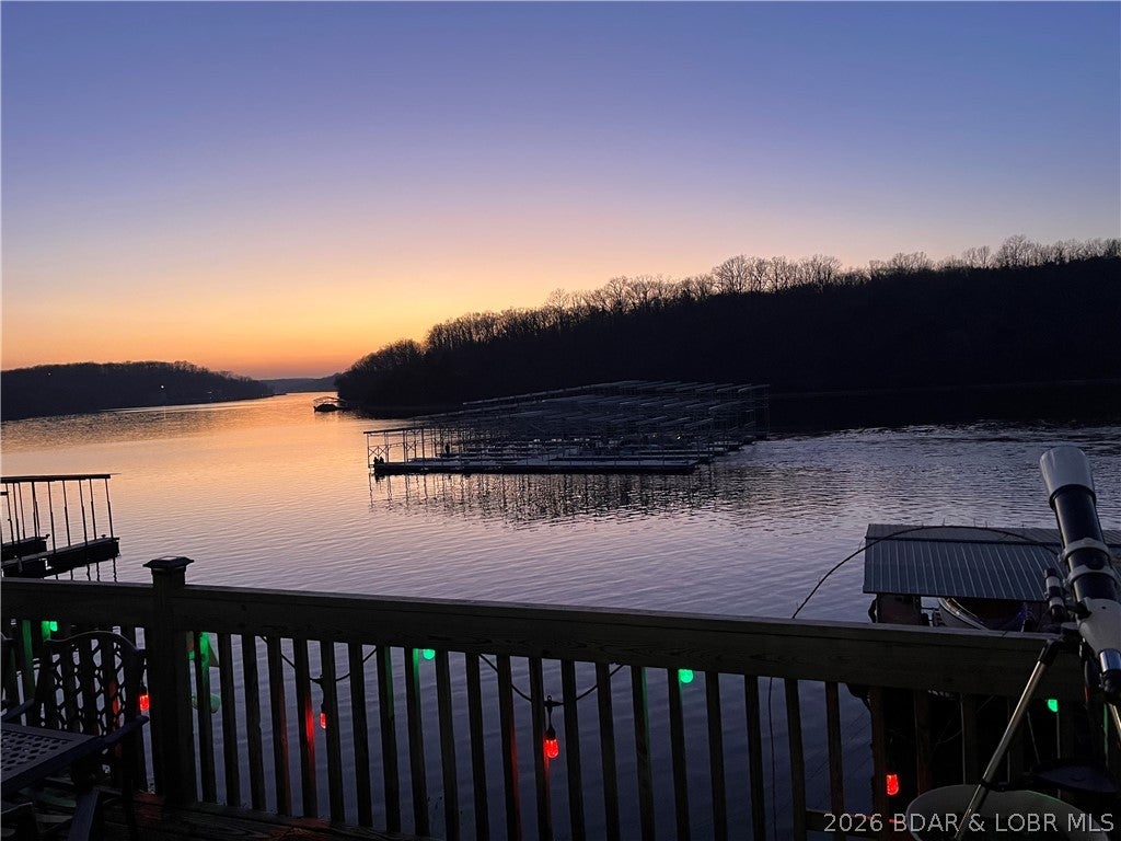 Under contract, listing will remain active until inspection contingency is resolved. LAKEFRONT • 160’ SHORELINE • 2-WELL DOCK • REMODELED • This Stunning remodeled 1623 sqft,3BR/2BA lakefront home on over ½ acre with gentle shoreline & rare,premium deep water at the private 2-well dock with 8000# remote boat lift & double PWC lifts. Enjoy peaceful privacy, yet you’re just minutes by water from popular lakefront restaurants. Inside, the open main level features a newly remodeled kitchen with custom cabinetry, veined countertops, chef’s island, beverage bar, double oven, & stylish lighting. The dining area opens to spacious deck & lake views. The living room blends modern updates with authentic Ozark character, highlighted by the original stone wood-burning fireplace. Upstairs, a sleek modern staircase leads to, Den/office, two bedrooms with oversized bunkbeds, Primary suite with lake views, a linear crystal fireplace & two closets. Outside, enjoy a large covered patio,wrap around deck, firepit & garden area, abundant parking & an easy low-step path to the lake. Walk in crawlspace, for utilities & storage. A rare combination of privacy, deep water, gentle access & extensive shoreline