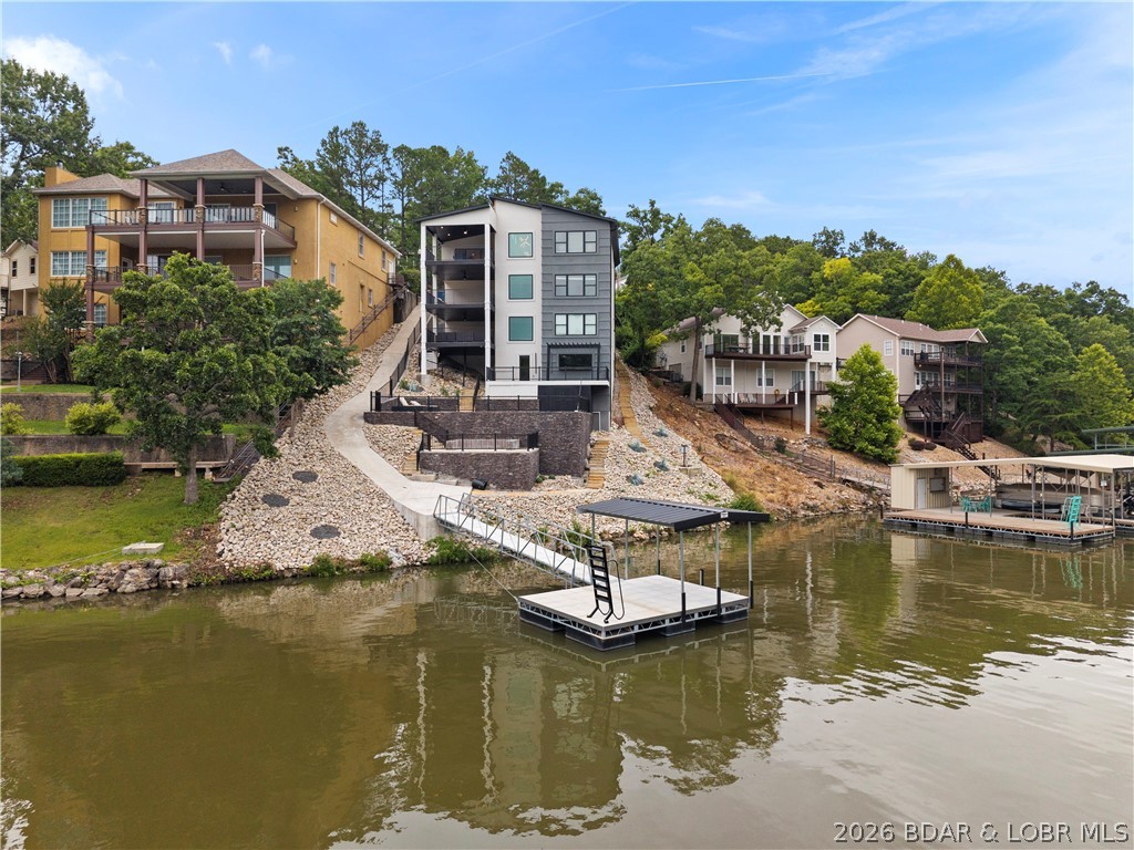 Experience luxury lakefront living in this fully furnished, turnkey masterpiece with stunning stucco and stone curb appeal. Professionally designed by Hockman Interiors, this exceptional home offers 8 bedrooms, 6.5 baths, four levels of living space, & breathtaking 17 MM lake views with the protection of a quiet cove. Thoughtfully designed for entertaining, enjoy the indoor/outdoor bar lounge with custom concrete countertops, 85" TV, saltwater pool, firepit patio with custom concrete seating, game room, & spacious covered decks on every level. The gourmet kitchen features a dramatic waterfall island, Bespoke European glass appliances, butler's pantry, quartz and granite countertops, & designer lighting throughout. The luxurious primary suite boasts a spa-inspired bath & dream walk-in closet. Additional highlights include luxury plank flooring, maintenance-free decking, drive-thru garage with double doors & a swim dock with 14x20 boat slip. LOTS of potential here to install your own dream dock with slips up to 40'+ in length. Undeniable prime location by land & water in Osage Beach for daily convenience. Built for unforgettable lake memories and the ultimate waterfront lifestyle.