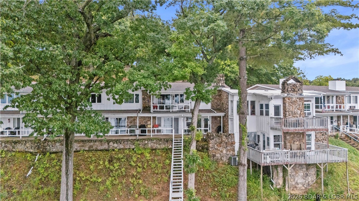 Enjoy panoramic lake views of the 4 Mile Marker from this furnished, one-level walk-in condo offering convenient access to the community pool and dock. Natural stone accents, two wood-burning fireplaces, and an open floor plan create a warm lake retreat designed for entertaining and everyday comfort. The spacious primary suite is complemented by an oversized guest bedroom with ample room for visitors, making it well suited for personal use, vacation getaways, or short-term rental potential. Step outside to the stairway leading directly to the community pool, dock, and Docknockers Bar & Grill below for effortless access to lakeside dining and recreation. Sold furnished and ready to enjoy from day one, this property also presents a strong investment opportunity with projected cash-flow potential. Whether you're searching for a lake-view vacation home, weekend getaway, or income-producing property at the Lake of the Ozarks, this condo offers a combination of location, convenience, and turnkey appeal.