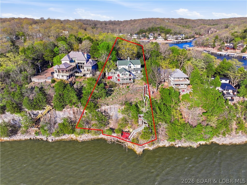 Step into a one-of-a-kind opportunity at the Lake of the Ozarks with this stunning Victorian-style home, formerly an original bed & breakfast and now a thriving vacation rental. Boasting 7 bedrooms and 4 private suites, this property is perfectly designed to host large groups while offering individual privacy—making it a proven income-producing investment. Perched on a scenic bluff, the home captures breathtaking sunset views over the main channel, creating an unforgettable backdrop for guests and owners alike. Enjoy direct lake access with the potential to add a dock, enhancing both value and convenience. This turn-key property comes fully furnished and ready to continue its success as a short-term rental or serve as a luxurious private retreat. Ideally located just minutes from Margaritaville and other popular lake attractions, you’ll love the blend of charm, history, and modern income potential. Whether you're an investor seeking strong returns or a second-home buyer looking for something truly special, this property delivers unmatched character and opportunity at the lake. Home includes a home warranty through 2028!
