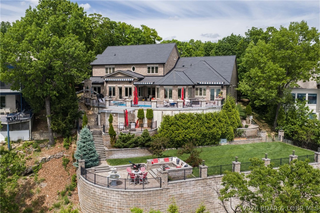 Refined living in the gated community of Cedar Crest—where luxury, privacy, & the best views at Lake of the Ozarks come together. Built by Thomas Construction, this all-brick estate is a rare find, offering 4,200 sq ft of main level living with zero-step entry and fabulous one level living. Inside, the quality is undeniable. Maple cabinetry, engineered heated hardwood floors, Pella windows, & designer lighting set the tone. The kitchen is a showpiece with a La Cornue range and stunning curved bar. The main level also features a grand living area with fireplace, bar, and a stunning suite with a spa-like steam shower. Upstairs offers 3 suites, a fitness room, wellness space, & an exceptional wine room. An elevator services all levels for convenience. Outdoor living is impressive with a patio featuring a pool, hot tub, & fireplace—all positioned to take in breathtaking views. Just below, “Windsor's Lawn” creates a one-of-a-kind setting with a beautifully crafted yard, firepit, & lush landscaping. Additional features include a DaVinci roof, generator, & 3-car garage with exceptional level parking. A property of this caliber, with this level of finish & usability, is a true standout.