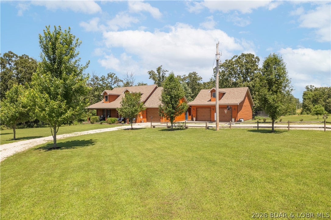 Situated on almost 10 acres, this 3 bedroom, 3 bath home combines lodge inspired design with custom details. Soaring vaulted wood ceilings, wood style flooring, natural wood trim and a floor to ceiling stone fireplace create an inviting feel. A wood staircase features custom railings with wildlife cutout designs. The main floor offers a living room plus separate family room. The master bedroom features a tray ceiling with ambient lighting, walk in closet and bath with soaking tub, separate shower and double vanity. Upstairs, the loft serves as the third bedroom with private bath featuring a jetted garden tub and separate shower. Extras include a pantry and laundry room with built in dog wash. The garage setup is a standout! In addition to the attached one car garage, there is a detached two car garage/shop that is INSULATED, DRYWALLED, HEATED AND COOLED for year round use. Above is a finished room ideal for an office or bonus space. Outside, enjoy a covered front porch, covered back deck, fenced yard, garden and children's playground. Exterior combines CertainTeed siding with Diamond Kote stained lap siding. A rare combination of acreage, custom details and incredible garage space!