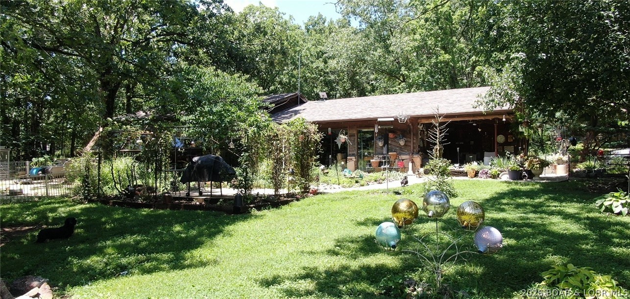 Escape the city to this beautiful 23-acre country paradise near Lake of the Ozarks! Masterfully designed for ultimate self-sufficiency and low energy costs, this unique 2BR/1.5BA homestead features a stunning attached greenhouse oasis seamlessly visible from your jetted garden tub. The innovative architectural design utilizes heavy insulated concrete earth-contact walls on the north and west sides to naturally regulate temperature, while the remaining walls feature premium 2x6 construction.Enjoy complete utility independence with a 305ft well tapping a high-yield aquifer, 20KW generator, and a wood cookstove. The land features a spring-fed creek, 2 acres of fertile pasture, and a beautifully engineered, stocked 10.5ft deep pond. Premium outbuildings include a 400sqft insulated guest cabin and a massive 1,728sqft metal shop wrapped in heavy copper grounding for full EMP/Faraday protection. Complete with an 8ft fenced orchard, animal yards, private shooting ranges, and a peaceful valley community. New roof & Bryant HVAC (2025). Absolute peace of mind awaits!