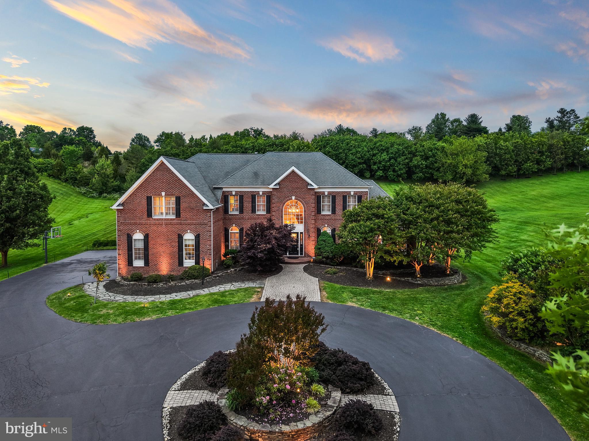 Welcome to 40890 Beechnut Rd—a stunning estate home in the heart of Leesburg set on nearly 4 acres of beautifully landscaped grounds. This brick front colonial offers 4 bedrooms and 4.5 baths, blending timeless design with an exceptional indoor-outdoor lifestyle. A circular driveway, attached 3-car garage, extensive driveway parking, and mature landscaping and hardscaping set the tone for this impressive property.

Outdoor living is truly a highlight, featuring a stone patio with a built-in fireplace, outdoor kitchen, and a granite and stone bar—an ideal setting for entertaining or enjoying the serene surroundings and gorgeous views.

Inside, a dramatic two-story foyer welcomes you in. A spacious sitting room and large living room/office space sit just off the gourmet kitchen. The kitchen features stainless steel appliances, recessed lighting, granite countertops, abundant cabinet and counter space, and a breakfast nook. A designated dining room provides a perfect space for gatherings, while the two-story living room showcases a striking stone fireplace and expansive windows that fill the home with natural light. A main level office adds flexibility for today’s lifestyle. Hardwood flooring runs throughout the main level, complemented by carpeted bedrooms and skylights that enhance the bright, open feel.

Upstairs, the second-story primary suite serves as a private retreat with dual vanities, a large stall shower, soaking tub, and generous proportions. Additional bedrooms are well-sized and thoughtfully arranged. The lower level offers flexible bonus space and ample storage.

Located in the Shenstone Farm HOA just off Leesburg Pike, this home offers convenient access to commuter routes, downtown Leesburg, parks, wineries, shopping, and dining. A rare opportunity to own a remarkable estate in an exceptional setting.