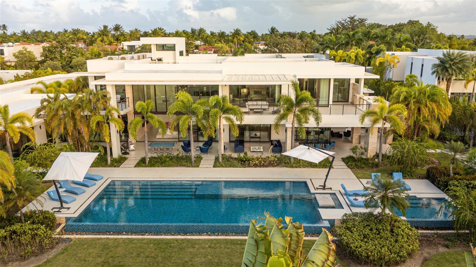 Situated within the prestigious Legacy neighborhood of Dorado Beach, this distinguished estate presents an exceptional blend of privacy, scale, and tailored luxury. Positioned on an expansive 4,800 square meter parcel, among the largest within the community, the residence enjoys a discreet setting along one of the resort’s most secluded streets.

Offering approximately 16,746 square feet of total construction, the estate has been thoughtfully conceived to accommodate refined daily living as well as high-level entertaining. Bespoke amenities include a private two-lane bowling alley, a half basketball court, and a series of elegant indoor and outdoor gathering spaces. The exterior environment is anchored by a resort-style pool, a covered outdoor BBQ grill and kitchen, and a poolside dining area designed for seamless entertaining.

The residence features three bedroom suites on the main level, each opening to private terraces, while the upper level is dedicated to two additional bedrooms and an expansive primary suite occupying its own wing. The primary retreat offers a generous private terrace, an oversized walk-in closet with center island, and a spa-inspired bathroom with an outdoor shower. A private office, an independent guest suite with its own entrance, and a dedicated salon space further elevate the home’s versatility and exclusivity.

Architectural highlights include double-height ceilings, curated materials and finishes, a custom hand-blown chandelier, and fully integrated smart home and audio-visual systems. This is a rare and distinguished offering within Dorado Beach, delivering exceptional land value, custom amenities, and a lifestyle defined by understated elegance and modern luxury.