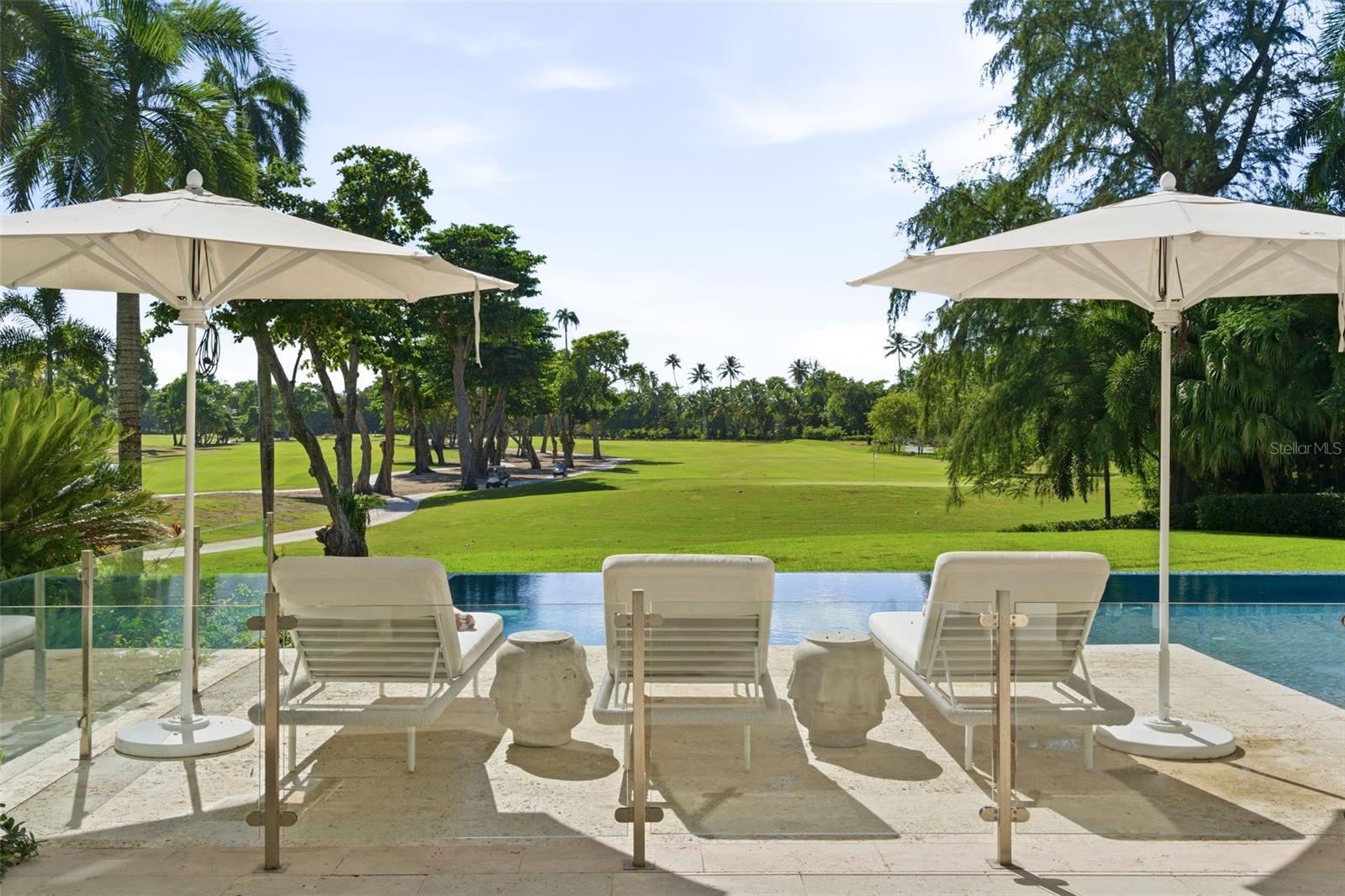Rodeo has its Drive. Dorado has Dorado Beach Drive.
Here, within the exclusive East Beach community, Villa D’Or stands as one of the most significant private estates ever offered within Dorado Beach Resort.  A five-year architectural expansion transformed the original East Beach residence into a truly one-of-one legacy property. Set on a premier 1.06-acre corner homesite, the estate encompasses 10,701 square feet of interior living space and 16,107 square feet of total construction, with direct ocean views and sweeping vistas across two championship TPC golf courses.
Inside, a 20-foot coffered-ceiling foyer is anchored by a Baccarat chandelier and dramatic coralina stone wall. Retractable floor-to-ceiling glass walls open the interiors completely to the infinity pool, tropical grounds, and fairways beyond. With seven bedrooms and ten bathrooms, the residence was designed to provide exceptional privacy for owners and guests.
The primary suite occupies its own ocean-facing wing, complete with a solid-stone soaking tub, steam room, indoor and outdoor showers, and private terrace. Five additional bedroom suites are positioned in a separate wing on the main level. The seventh bedroom is located within the second-level expansion—a feature found in no other East Beach residence—and was designed as a private guest or in-law suite with a kitchenette, custom Italian closets, and marble bathroom.
Also within the expansion is an acoustically treated room with a Wolf-equipped kitchenette, currently used as a classroom and designed to transition seamlessly into a private cinema. The third level was created for entertaining, featuring a dedicated office, temperature-controlled wine cellar, cigar humidor, custom backlit onyx bar illuminated by Baccarat fixtures, and an expansive sunken lounge.
Above it all, the rooftop features a glass jacuzzi with panoramic ocean and golf course views, along with an outdoor kitchen equipped with a Grillworks grill, beverage refrigerator, and ice maker.
As a Ritz-Carlton Reserve branded residence, Villa D’Or combines the privacy of a private estate with the services of one of the world’s most celebrated resorts. Owners may order room service directly to the residence, while hotel management provides ongoing care, including pool and window cleaning through the residential association. Steps from the resort’s restaurants, private beach club, and Spa Botánico, Villa D’Or offers effortless access to the best of Dorado Beach from an address that is impossible to forget.
