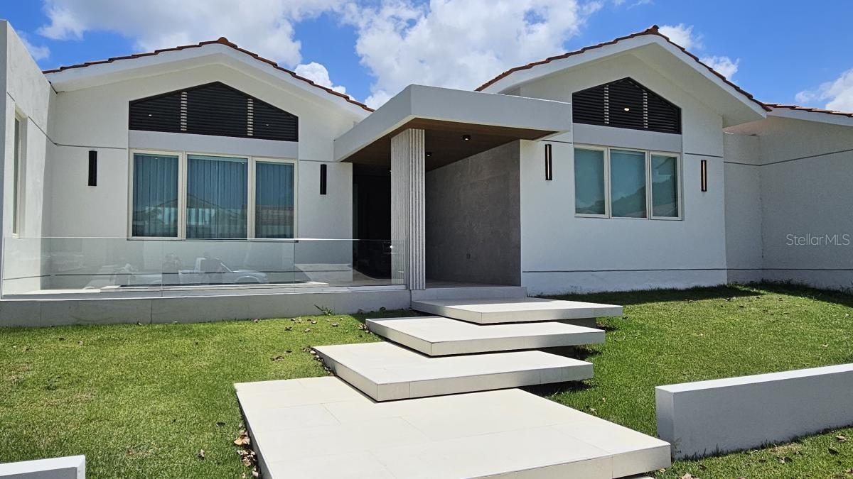 Located in Sabanera Dorado, Puerto Rico, this corner lot with 1,150 square meters of land has a newly constructed and renovated residence that was expanded to 5,800 sf features 5 in suite bedrooms, 5 full bathrooms, and a powder room.

The property features high ceilings and thoughtfully designed living spaces, including a great room, family room, dining area, and outdoor terrace with exquisite tilework throughout. California Closets in all rooms. The design allows for creating an in-law's suite in front of the pool with its own parking and entrance.

The property offers a serene retreat with a sparkling saltwater pool surrounded by lush landscaping. 5 parking spaces plus a golf cart space. Equipped with a 30KW generator, solar water heater, 2,000-gallon cistern and a solar water heater. The kitchen is equipped with Monogram appliances and there are 10 split system air conditioners to climatize all areas of the home. Located within a gated golf cart community, residents enjoy resort-style amenities, including community pools, a gym, tennis and basketball courts, as well as a convenience store, the renowned TASIS school, and 24/7 security