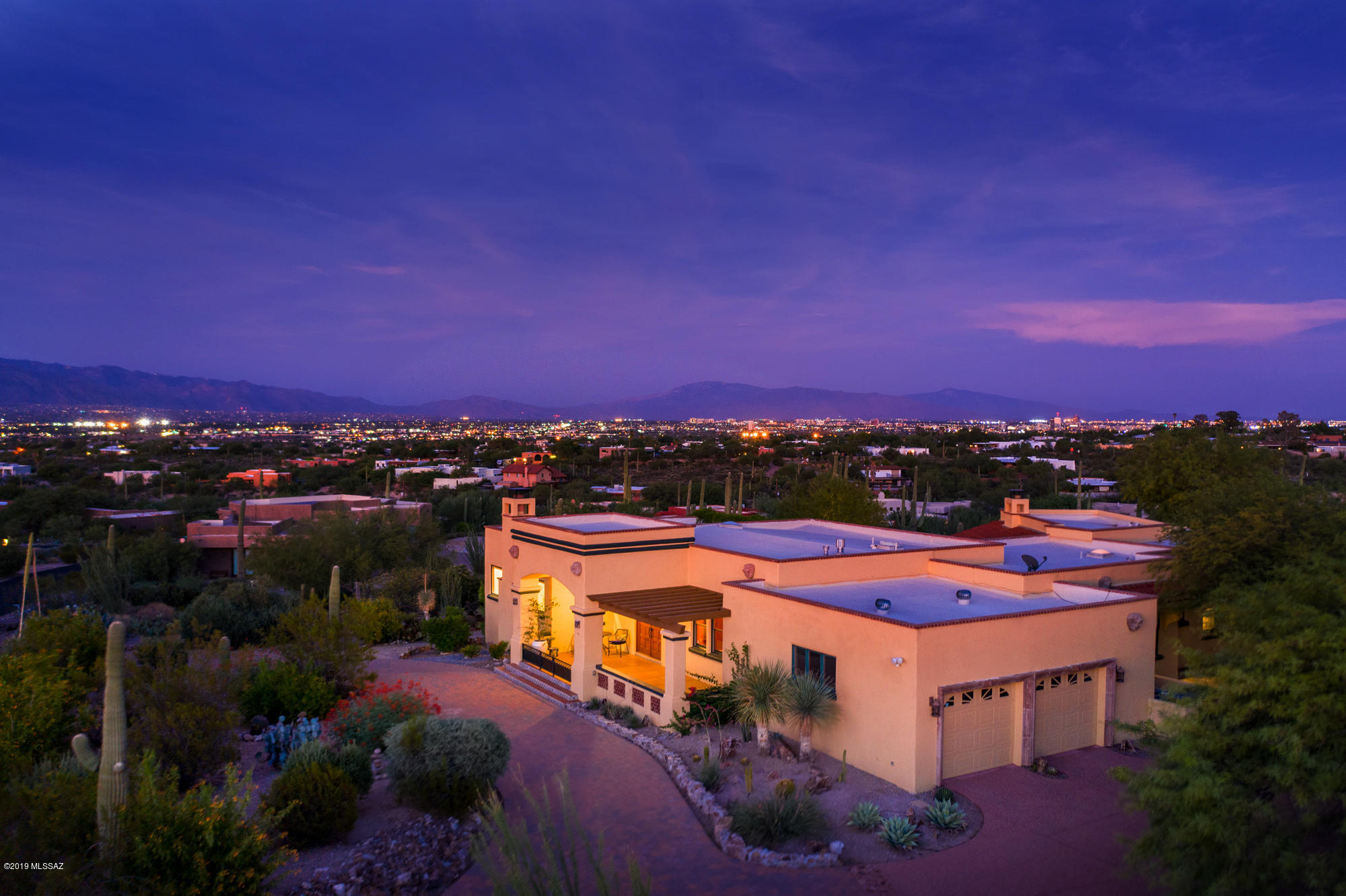 Enchanting Spanish-inspired custom home nestled on a hilltop acre in a gated community offering panoramic city & mountain views! Fine craftsmanship flourishes in this stunning home that seamlessly blends upscale elegance with rustic, old-world charm and is the epitome of Tucson living! Unique architectural elements including wood-beamed ceilings, Spanish tile accented floors/archways, and beautiful concrete floors & stonework. Light-filled formal living room overlooking the backyard, expansive gourmet eat-in kitchen, and stylish family room. Divine owner's suite with sitting area and spa-like ensuite bath. Adjacent bonus room for studio/office. Tranquil backyard retreat with wrap-around porch, lush vegetation, sophisticated lap pool, ramada, outdoor kitchen, and private basketball court.