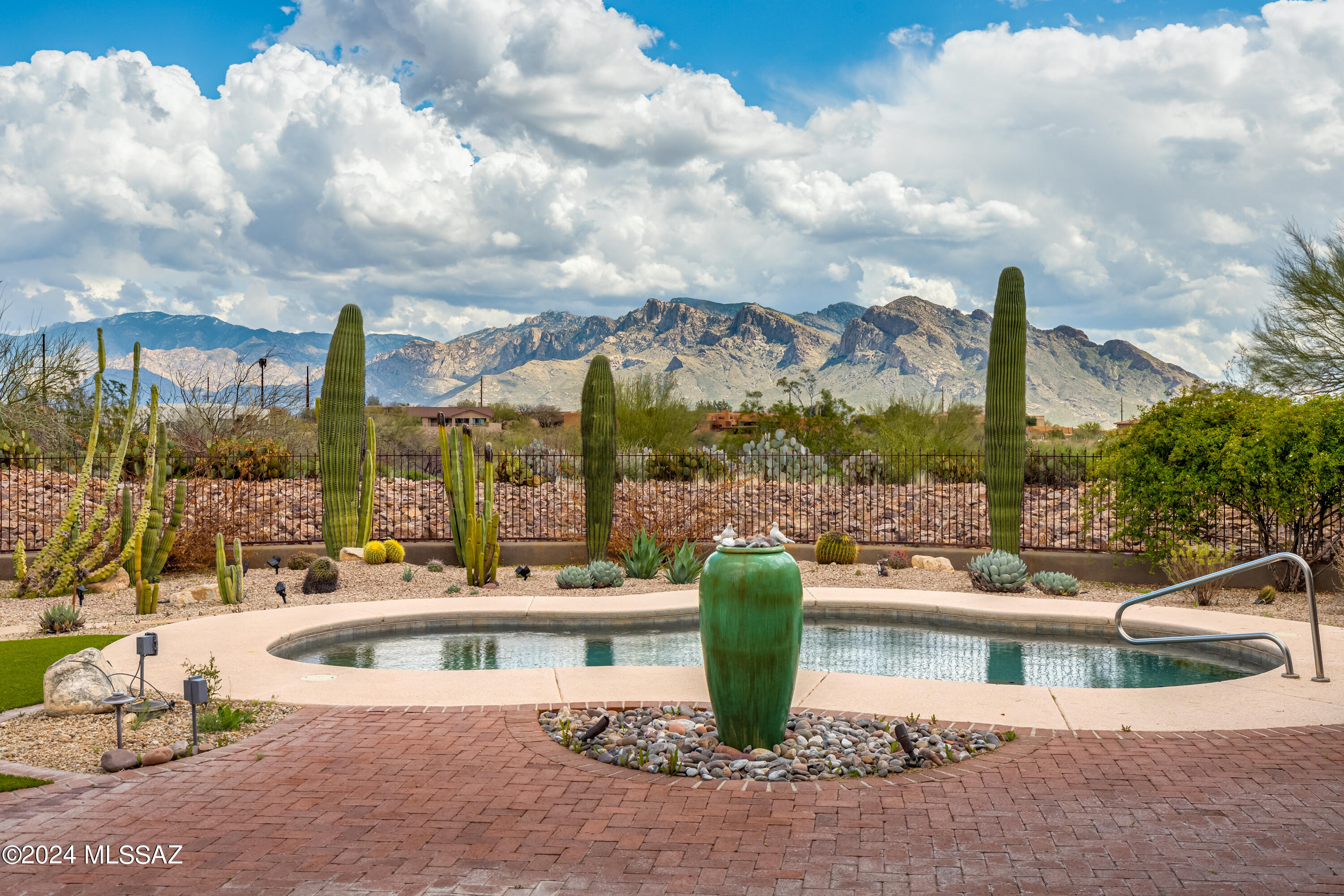 The perfect fusion of Southwest charm & breathtaking outdoor beauty in the perfect setting. This exquisite 4BR/3½BA single-story home in Chaparral Heights, Oro Valley, has 3,476sf of luxury living on a premium 1+ acre lot w/unparalleled views of Catalina Mountains & Pusch Ridge. TJ Bednar home built in 2005 has scored stained concrete floors, knotty alder doors & cabinetry, plank & vega beam ceilings, wood plantation shutters & Kiva gas fireplace in living room. Gated courtyard has brick pavers. The kitchen, open to the family room, has stainless appliances, gas cooktop, granite counters, desk area, wine rack & spacious pantry. 4th Bedroom is guest quarters w/its own bath & private entrance. Providing an ideal space for relaxation & retreat, the Den/Library has built-in shelves & window bench seating offering a tranquil getaway. Formal dining area for family gatherings or social entertainment. Luxurious master suite has spa-like bath, walk-in closet & access to the covered patio. Covered patio offers a serene retreat, overlooking the resort-like rear yard w/heated saltwater pool, fireplace w/banco seating, flagstone & brick pavers, water features, lush easy-care landscaping & gazebo all set against the backdrop of the Catalina Mountains. Oversized 3-car garage includes a workshop area & storage cabinets. Conveniently situated near top-notch restaurants, shopping, libraries, parks, hiking trails, bike paths, and the Community Recreation Center with golf, a driving range, fitness center, and pickleball and tennis courts, this property offers a harmonious blend of luxury and lifestyle.