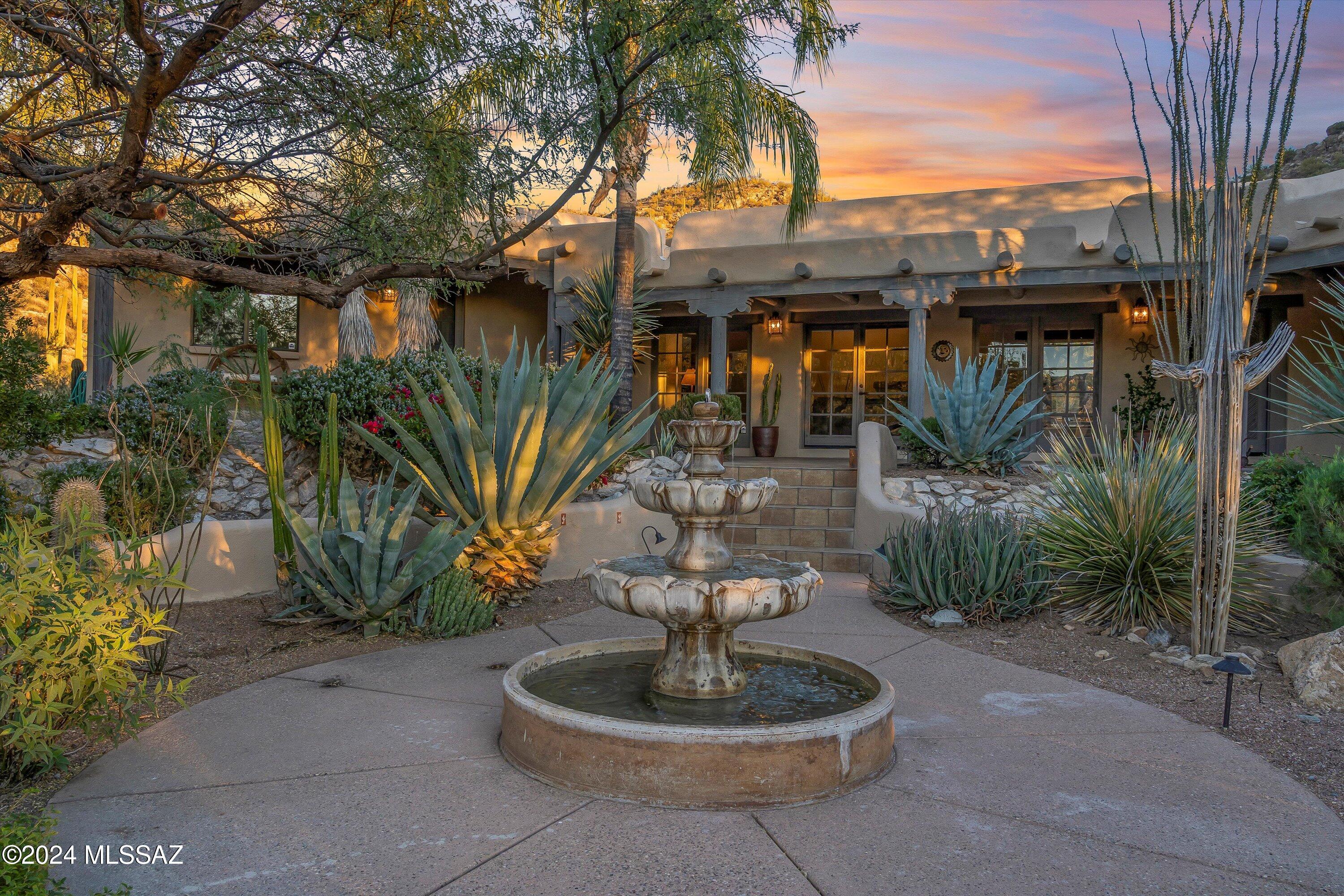 Escondido Ranch, located in NE Tucson Arizona, an area known for its relaxed lifestyle and easy going living. This exceptional Santa Fe Home, located on an expansive 10.81-acre parcel, provides a rare opportunity to embrace the peace and serenity of desert living. This property offers breathtaking panoramic views of towering Saguaros and the pristine beauty of the desert landscape—truly a one-of-a-kind setting as it adjoins Arizona Land Trust and the Coronado National Forest.A well-maintained 3,060 square foot home features 4 spacious bedrooms and 3 bathrooms, thoughtfully designed to complement the natural surroundings while providing ultimate comfort and privacy. From the moment you enter the property, you will be enchanted by the seamless blend of indoor and outdoor spaces that create a sanctuary perfect for relaxation and entertainment.
 From the moment you enter the property, you will be enchanted by the seamless blend of indoor and outdoor spaces that create a sanctuary perfect for relaxation and entertainment.
The outdoor spaces are nothing short of extraordinary, each carefully designed to enhance the natural beauty of the environment. Step north of the home and you'll discover a charming bird-feeding area that draws a variety of Southwestern bird species, offering a delightful spectacle of nature right at your doorstep. Adjacent to this tranquil space is a Kiva fireplace, a cozy retreat for the seller and the perfect spot to unwind under the stars. A luxurious jacuzzi nearby offers yet another vantage point for enjoying the stunning desert sunsets and the awe-inspiring night skies that this location is famous for. Whether soaking in the warm water or simply relaxing, this serene space offers the perfect place to rejuvenate and savor the surrounding beauty.
This area of the property also includes an enclosed herb garden, thoughtfully designed to provide optimal growing conditions even during the heat of summer. Just beyond this, you'll find four tree trenches, each equipped with a dedicated irrigation system, making this the perfect space to create your dream orchard. Arizona is well known for fabulous orange and lemon trees.
As you explore further, you'll encounter multiple patios that provide unique perspectives of the expansive grounds. The central patio, with a covered area and hammock, is ideal for leisurely afternoons and evening meals, offering a peaceful retreat for relaxation and connection with nature.
Just east of the home lies a magnificent Pebble Tech swimming pool, which serves as the perfect place to cool off and unwind. A gentle waterfall adds an element of tranquility to the pool area, further enhancing the peaceful ambiance of the property. Continuing along the tree-lined path, which is illuminated by Kon tiki lighting, you'll be led to an incredible overlook of Milagrosa Canyon. Here, the views stretch across hundreds of acres of untouched national forest and state trust landan idyllic setting for nature lovers, hikers, and outdoor enthusiasts.
The beauty of this remarkable property is not just in its size, but in its ability to offer a sense of peace, privacy, and connection to the surrounding natural world. This is more than just a home; it's a sanctuary where every corner offers a new opportunity to experience the magic of desert living.
Whether you're drawn to the stunning vistas, the luxurious amenities, or the tranquil outdoor spaces, this extraordinary property offers a unique and unparalleled living experience. Don't miss the opportunity to make this desert retreat your own. Schedule a private tour today and immerse yourself in the beauty and serenity of this exceptional home.
A once-in-a-lifetime opportunity to own a desert oasisschedule your showing now!