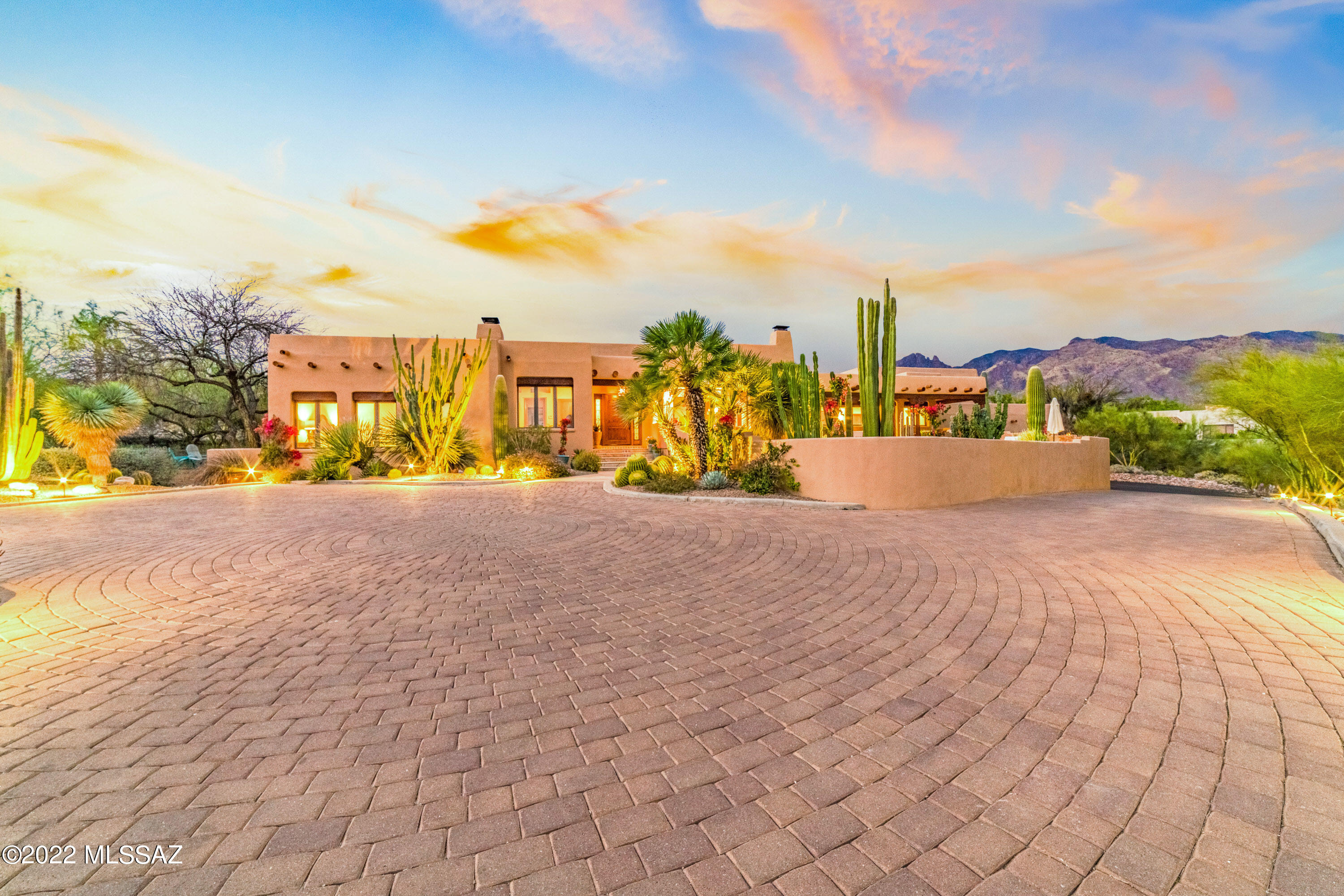 Back and better than ever before, this magnificent home designed and built by respected local builder Mike Wachs for his own personal residence features 5 bedrooms, 4 bathrooms and has just undergone an extensive remodel by the current owners who have introduced a modern Southwest vibe that has transformed this already stunning authentic Santa Fe residence into a sophisticated and modern home with finishes one would expect in a home of this caliber and that embodies the wonderful Tucson desert lifestyle. This home was perfectly placed far back from the quiet street on a prime 1.88-acre hilltop lot with commanding mountain and city views with ultimate privacy in one of the Foothills finest gated communities, Catalina Foothills Estates #10. As you approach up the long private driveway, you are welcomed by an extensive collection of exotic cacti and rare desert plantings by Plants of Distinction that perfectly enhance the homes style. Inside you will find stunning Saltillo tile floors with a rich patina that complement the warm wood high beamed ceilings, & walls of windows . Freshly painted on the inside, the neutral white palate perfectly enhances the many custom tile details and superior craftsmanship this home exudes. As you enter the home, your eyes are drawn to the spacious and inviting living room featuring a beehive fireplace, a wet bar w/designer tile wall and wine fridge ideal for entertaining, a large picture window that perfectly frames the city lights at night and leads to the formal dining room for intimate gatherings.  The spacious chef's kitchen features granite counters, newer stainless appliances, center island w/Wolf cooktop, butler's pantry and an eat-in breakfast nook for causal family dining. The spacious owner's suite offers a cozy reading area w/see through fireplace, city light views from the bedroom, a spa like bathroom w/large walk in closet, an exercise room w/access to a private patio and is adjacent to the 5th bedroom or private home office. The guest wing offers a main floor suite, two bedrooms & update bathroom upstairs and a bonus loft/rec space. Two inviting outdoor living areas offer the best of both worlds- the rear North facing patio with a kiva fireplace, lush mesquite trees and stunning views of the Catalina Mountains & Finger Rock and the front South facing covered patio ideal for cocktails and al 'fresco dining overlooking the pool and city lights. The oversized 3 car garage can easily accommodate a lift for additional car storage or a small RV.
