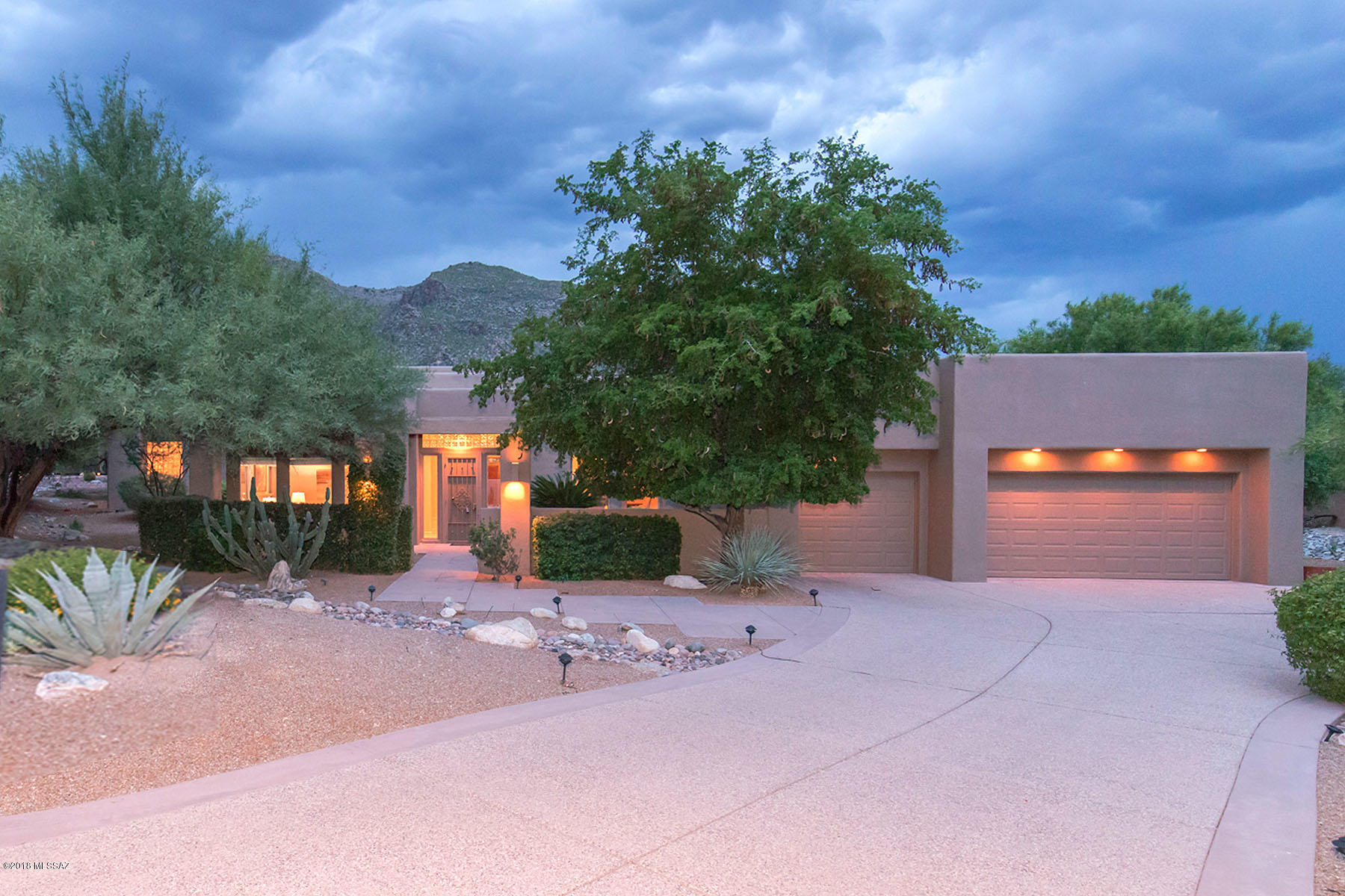 A gracious hidden and very private Ventana Canyon gem is now available to be viewed by discriminating buyers. In a quiet, well-established prestigious guard-gated community, this warm contemporary home is surrounded by rich mature mesquites and ancient palms. An elegant entry is through the gated courtyard guarded by a giant sego palm. Inside, this home is well lit with natural light filtering through the many large windows throughout the home. The soft neutral and luxurious travertine flooring and new berber-style carpeting contribute to the home's tranquil feeling. There is lots of room for everyone, with a cozy sitting area embellished by a gas fireplace, perfect for intimate chats. A well-sized dining room with a built-in buffet overlooks the entry courtyard. There is a comfortable flow into a generous greatroom with an ultra-high ceiling and graced with a bar area featuring fridge and sink and also a built in entertainment center. Tall windows provide magnificent views looking up to the Catalina Mountains. A large kitchen with granite counters, GE appliances, an ample walk-in pantry and convenient desk opens to the spacious glassed-in breakfast area looking out to leafy green mesquites and mountain views beyond. Sliding doors lead to the zen-like rear yard, an elegant spot accented by an attractive fountain flowing into a lovely series of shallow ponds that create an almost "spa" sense of tranquility. Multiple entertaining spaces beckon, all private and with north-facing Catalina Mountain views. The master suite is magnificently spacious, with tall windows providing soothing views of the rear fountain and ponds and mountains beyond. There's a door out to a small intimate patio for a quiet cup of coffee. A substantial walk-in closet is well-outfitted with built-in storage. The master bath feels quite "masterly".  Large windows are hidden by more  mature leafy mesquites. The oval jetted tub is set in a broad travertine surround ready to hold a glass of chilled Chardonnay during an extended bubble bath. There are also two separate vanity/sink areas that include a seated make-up area, a travertine shower and separate WC. On the opposite side of the home are three additional bedrooms, one ensuite and the other two sharing a well-planned "Jack & Jill" bath area. This side of the home is adjacent to a wash providing additional privacy from neighbors. The laundry room provides a sink, large counter area and lots of storage. A large three-car garage provides additional storage. Luxurious features throughout this ultra-custom home include high ceilings, 8' doors, fine fixtures and high-end fittings and lighting. The home is located In the Ventana Country Club, with an award-winning golf course circling throughout the area and excellent recreational facilities including a pool & spa, clubhouse, and restaurants. Conveniently located with quick access to outstanding shopping, dining, world-class entertainment, top rated medical care, and all needed services. Please call for your private showing.