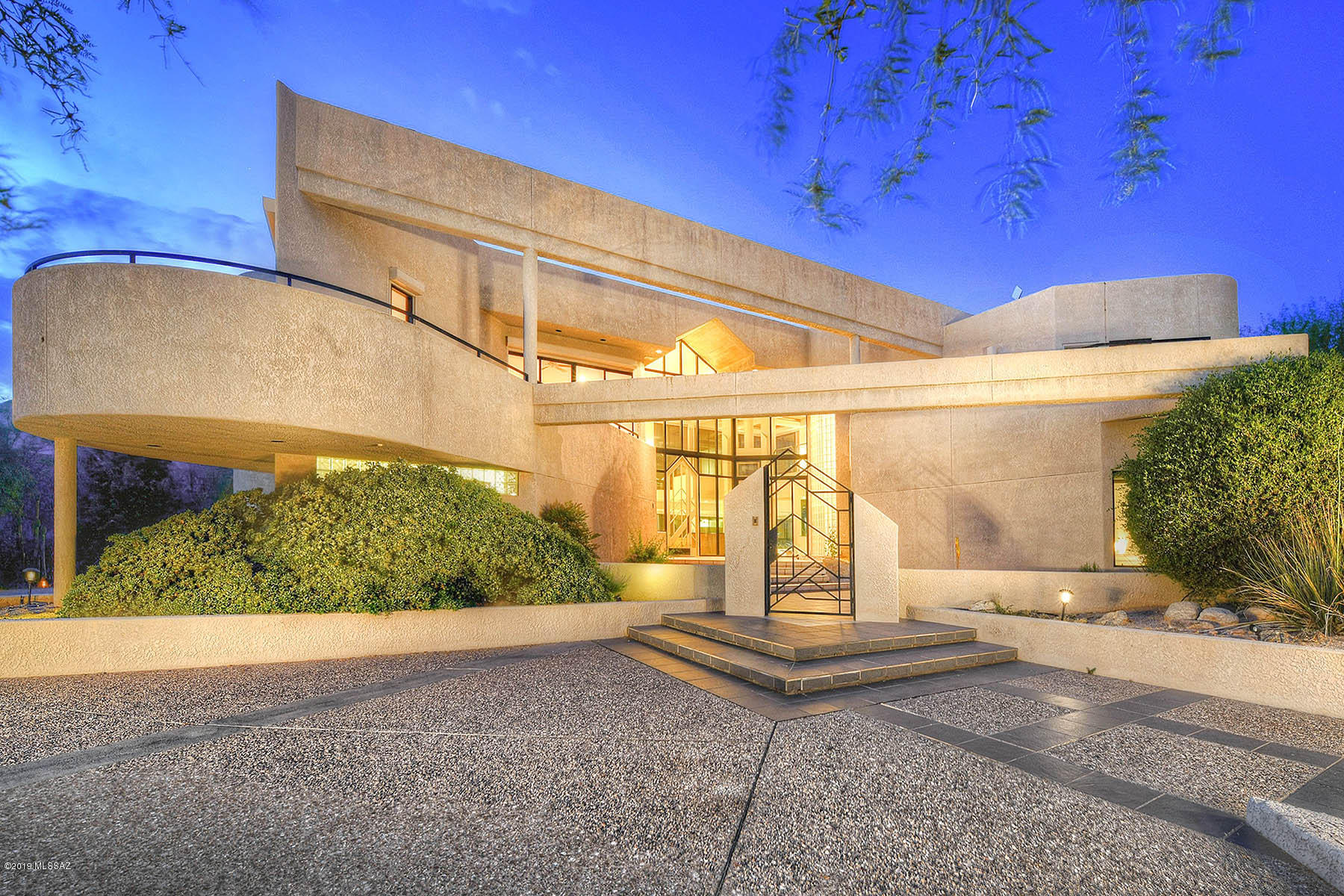 Spectacular custom home encompasses modern elegance mixed with contemporary exquisite lines.  Featuring 20 ft walls of windows, this property showcases captivating views of the Catalina Mountains. Italian Stone courtyard greets you and the open living concept allows for a variety of uses.  With over 4000 square feet inside, you will enjoy the generous open kitchen with island and built-in breakfast bench. Spiral staircase leads you to the open loft/family room with private bath. Master suite has its own laundry, large walk-in closet & balcony where you can enjoy Tucson's sparkling city lights. 3 cozy fireplaces and extra work out room.  Retreat outdoors to your north facing back yard in style with glass wall, pool & spa. Spacious 3 car garage with extra storage. One of a kind-unique home!