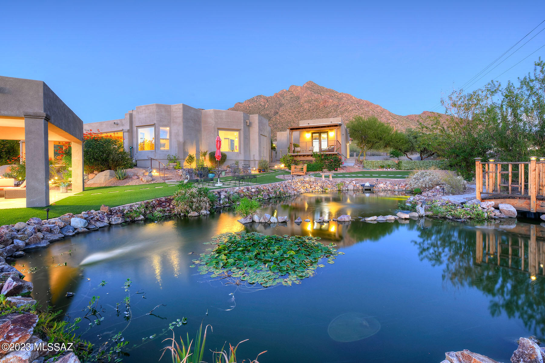 Stunning soft contemporary on almost 1 acre near Pusch Ridge w/city, mountain & sunset views. Amazing one of a kind property w/incredible 40ft.x20ft. fresh water pond w/fish. Totally remodeled home w/3661 sq.ft. in the main house, foyer entry, equisite living room w/library w/walls of windows, beautiful built- in lighted bookcases & art display niches, high ceilings throughout, polished porcelain tile floors, lovely dining area w/bay windows, large gourmet island kitchen w/granite countertops, stainless steel appliances, gas stove top, refrigerator, wine cooler, pantry, family rm w/fireplace & expansive doors to the covered patio. 3 bedrooms + office w/built-ins or 4 bedrooms & 4 baths including master w/fireplace , lux. bath w/jetted tub, sensational shower, walk-in closet, laundry rm & 2 car garage in the main house. Plus the 1136 sq. ft. guest house built in 2019 w/Great Room, kitchen, 2 bedrooms, 2 baths, laundry room & a small RV garage. Enjoy the resort like backyard w/gas heated pool, spa, covered patio w/fireplace, ramada w/outdoor kitchen, BBQ, artificial turf & the fabulous pond. Views, views, views!!! Guest house is Perfect for Airbnb or VRBO. This property has it all!