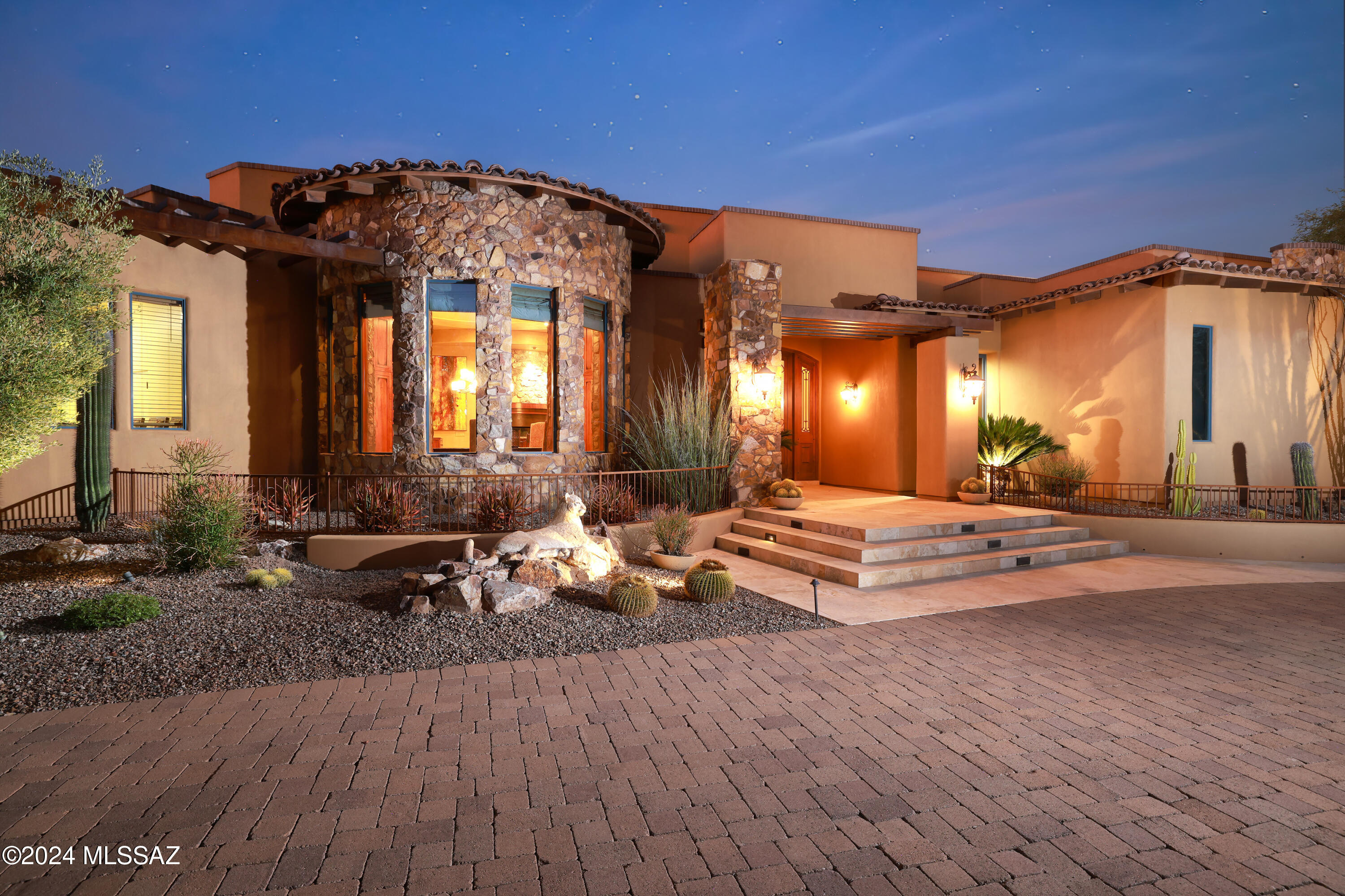 This exceptional Italian inspired Mediterranean villa is being offered practically turnkey, with most furniture, artwork, kitchenware, linens, etc.  Designed by Marc Soloway and built by Cutshaw Yeager, the home is ideally situated on a very private one-acre lot just 500 yards from the first tee, clubhouse, and restaurant of the Stone Canyon Club. The main house is 4,427 sq ft, with 3 bedrooms and 4 baths.  There is an additional bedroom and bathroom in the 479 sq ft casita. Throughout the home you will be impressed with the artistry, craftsmanship, and attention to detail. The signature feature of the home is certainly the tear drop shaped fireplace in the great room with the impressive floating chimney stack above. The natural stone, dark chocolate tile, and stunning hardwood.. accents are truly a work of art. The unique design allows you and your guests to enjoy the fireplace from all three sides. Next, you have a true chef's kitchen, featuring the travertine range hood with the "golfing kokopelli." There is a 48"  double oven Wolf Range with four burners and French top, built-in Wolf electric steamer, 60" Viking Professional side-by-side refrigerator/freezer, 5' X 7' island with copper prep sink and functional drawers and cabinets on all four sides, deep copper farm sink, Bosch dishwasher, two Fischer-Paykel dish drawers, and large walk-in pantry. There is bar seating at the island as well as the curved breakfast bar. As an extension of the kitchen there is a large butler's pantry featuring plenty of counter space with abundant cabinet and drawer storage, a Viking icemaker, a GE Monogram beverage cooler, and two under cabinet plate warmers. The butler's pantry opens to the circular formal dining room featuring a 90" diameter circular dining table for up to 10 place settings.  Of particular interest is the elegant ceiling and soffit work and the stone accent walls. Behind the wet bar and liquor cabinet is a hidden window which opens to the climate-controlled wine room featuring the "drinking kokopelli" and storage for up to 600 bottles. Notice the unique copper sink and 2-inch chiseled edge of the wet bar. In the great room, the artistry and craftmanship found in the signature fireplace continue on the opposite side of the room with the custom designed hardwood accent wall which displays three stunning petrified wood slabs and accommodates an 80" curved Samsung SUHD TV. On the north wall, you essentially have a wall of windows and glass sliding doors overlooking the incredible backyard and Tortolita Mountains. There is travertine tile throughout most of the home, with engineered hardwood flooring in the office and master bedroom. A custom luxurious wall-to-wall area rug lays on the travertine tile in the media room. There are also several custom tile inlays at the entry foyer, the foyers to the master suite and guest wing, and the master bathroom. The ceilings are simply spectacular and an embodiment of design and craftmanship. The 14' high great room ceiling features wood beams radiating from the signature fireplace.  Throughout the rest of the home, there are extensive soffits and cove details.  All the coves feature soft accent lighting.  Just off the master suite is an intimate office featuring a double-sided desk, built in cabinetry and shelves, hardwood floors, and plantation shutters. The luxuriously furnished master suite with circular sitting area is perfectly situated on the NE corner of the home, featuring hardwood flooring and high ceilings. Sliding doors open to the back patio and offer easy access to the roof deck. The master bathroom is bright and spacious, with a lighter shade of stone tile, two Solar-tube skylights, two separate vanities, large make-up area, elegant pewter chandelier and wall sconces, a raised Hydrosystems jetted tub, and walk in shower with multiple shower heads and wall jets. The 200 sq ft master closet is brilliantly organized by California Closets, with hat racks, shoe racks, ample shelving and hanging space, cabinets and center island with locking drawers. The media room features beautiful hardwood cabinetry, shelving, and accents, leather tile wall covering, and black-out window coverings. The two en-suite guest bedrooms feature large bathrooms and large walk-in closets.  One of the bedrooms has an exterior door for easy access to the back patio and pool area. The stunning powder room features a copper sink, dramatic two-tiered quartz countertop with rich veining, custom mirror, along with Venetian glass wall art and two metal sculptures. Your guests will be in Heaven in the almost 500 sq ft casita. It is luxuriously furnished and features 12' ceilings, hardwood flooring, built-in desk and shelving, coffee station with Sub Zero mini-fridge, walk-in closet, and spacious bathroom with both a soaking tub and separate shower. At the SW corner of the home is a large bright laundry room with skylights, an Aquatica laundry sink, abundant cabinets and storage, vented AV cabinet, ironing station, and LG Steam Washer & Steam Dryer. Step outside to arguably one of the best back patio hardscapes in all of Stone Canyon.  Several thousand square feet of travertine decking with over 1600 sq feet under roof.  Roof heights of 15 to 20 feet, supported by massive beams, and finished with tongue and groove plank.  The beautiful crescent shaped pool is accented by two fire bowls which waterfall into the pool. The spa doubles as a soothing water feature as the water overflows the infinity edge. Both the pool and spa are salt-water, self-cleaning, with Pebble Tech finish. Next to the custom designed firepit is an impressive outdoor kitchen with 42" Alfresco rotisserie grill, prep sink, beverage cooler, storage, and lots of bar seating.  The backyard is extremely private with north facing panoramic views of the Tortolita Mountains and partial views of the Catalinas. There is also a little pathway to the south side of the Stone Canyon Club driving range. There is an oversized 3 car garage with epoxy floors, 10' x 20' storage closet, skylights, storage cabinets, and workbench.
+++++++++++++++++++++++++++++++++++++++++++++++++++++++++
14133 N Hohokam Village Pl
Highlights:
Total Sq Ft: 4,806  (Main house 4,427 sq ft  w/ 3 bedrooms and 4 bathrooms, Guest house 479 sq ft w/ 1 bedroom and 1 bathroom)
Lot size: 1.06 acres
Architect:  Marc Soloway
Builder: Cutshaw Yeager Construction
Interior Design: Inspire Design (Heather and Chet Douglas)
Miscellaneous
Zeta Rod whole-house water conditioner
Central Vac
Four zone drip irrigation
Three HVAC units, 2 H2O heaters in main house, 1 each in casita.
Additional storage closet beneath the stairs to roof deck.
All parapet walls are capped with brick which drastically reduces or eliminates the typical maintenance required for traditionally stuccoed parapet walls.
Fire suppression system.
400-amp main electrical panel, 200-amp sub panel in garage, 125-amp sub panel at casita, 75-amp sub panel at pool equipment.
Saltwater chlorination system for pool.  
Pentair easy touch control for pool and spa with remote control.
Citrus Trees at east side of back yard.
Dynamic Low EMF FAR Infrared Sauna in garage is included
The two limited edition Piaggio Scooters in garage are included.