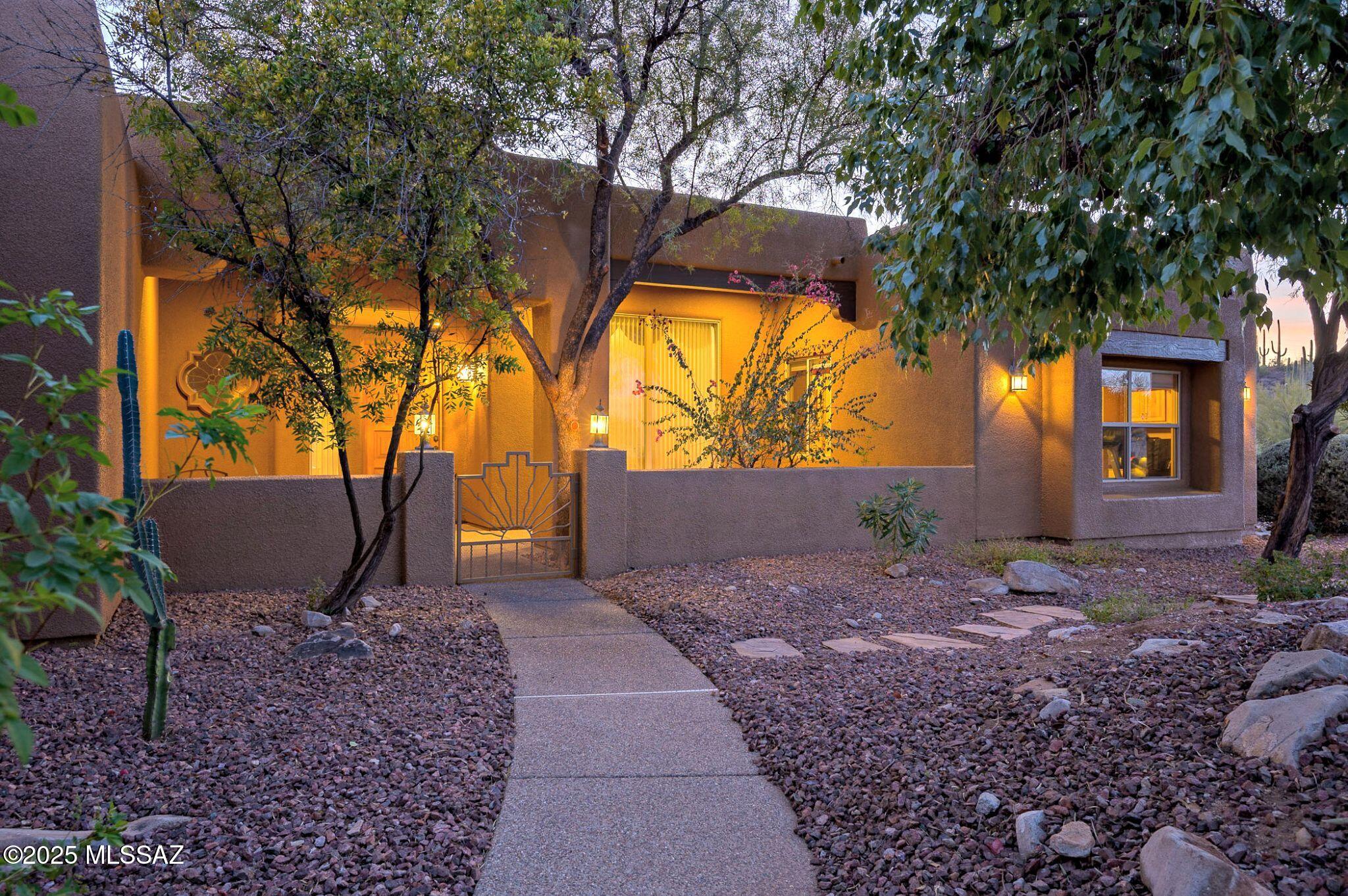 This stunning 4-bedroom home is nestled in a private gated community, offering both privacy and tranquility on over an acre of lush desert land. The property has been meticulously maintained and upgraded throughout, showcasing a perfect blend of finishes and charm.
You'll be greeted by a courtyard entrance, then Inside you'll find spacious, open-concept living areas with abundant natural light, high ceilings, and walls of windows inviting in the beauty of the desert. The kitchen is a chef's dream, featuring granite counters, large center island, custom cabinetry, and plenty of storage. Each of the four bedrooms provides ample space, with the primary suite privately tucked away from the others offering a private retreat. 
Step outside where you'll enjoy breathtaking views and ultimate privacy, making it an ideal space for entertaining or relaxing. Whether you're lounging on the patio or exploring the lush landscaping, this property provides an idyllic, peaceful escape while being conveniently located near local amenities, hiking, commuting or even the University of Arizona just mere minutes away. This is the ideal balance of luxury, comfort and serenity.