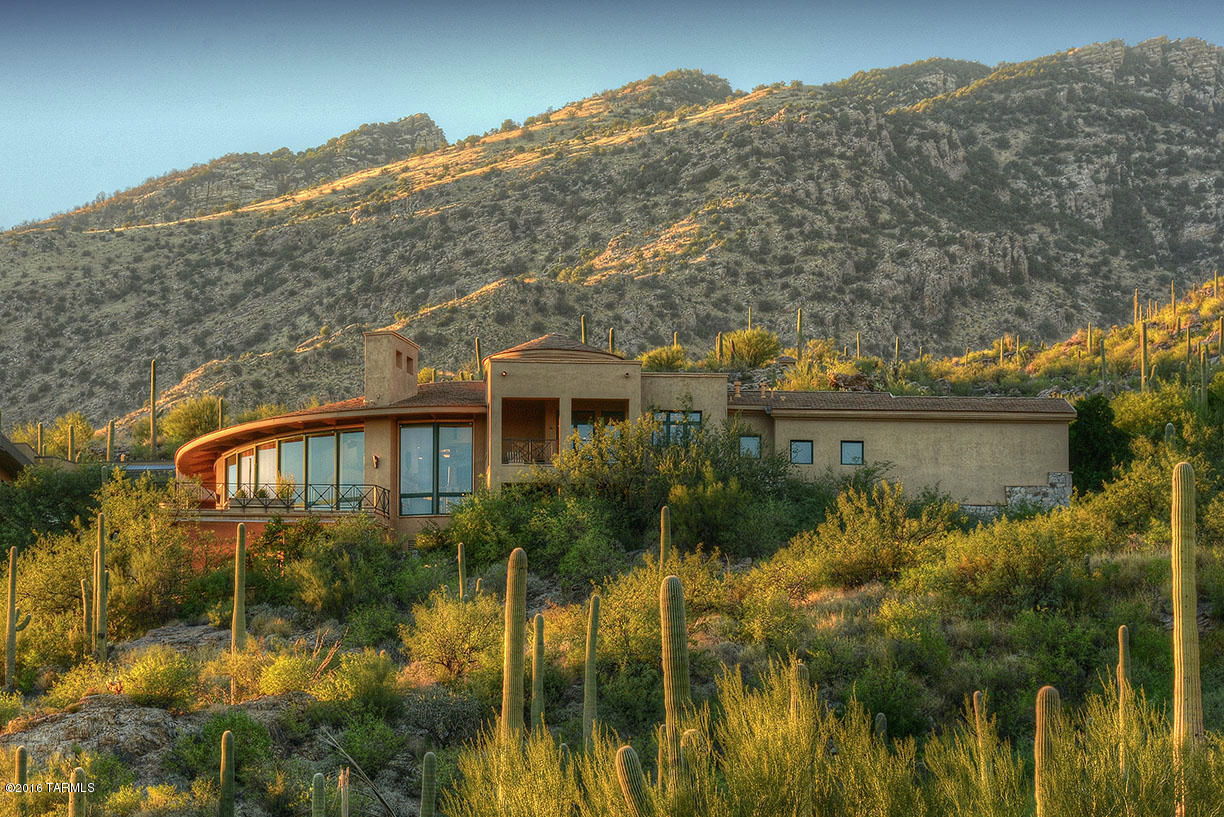 Outstanding Bill Gansline designed soft contemporary high above the city on the mountain in prestigious Ventana Canyon Mountain Estates with 5049 sqft. Stunning courtyard entry through natural boulders with pond and waterfall leads into great room with soaring beamed ceiling, walls of glass, sweeping 180 degree city, mountain, golf course and sunset views. This all masonry stucco home with 3 bedrooms and activity room with Murphy bed (could be 4th bedroom) features natural stone and alder wood floors, gourmet kitchen with breakfast nook and private balcony, gracious master suite with dual vanities and closets, standalone tub and library with soaring beamed ceiling with floor to ceiling bookshelves. Three car garage, balconies, vistas, covered patios with pool & pool bath, outdoor kitchen.
