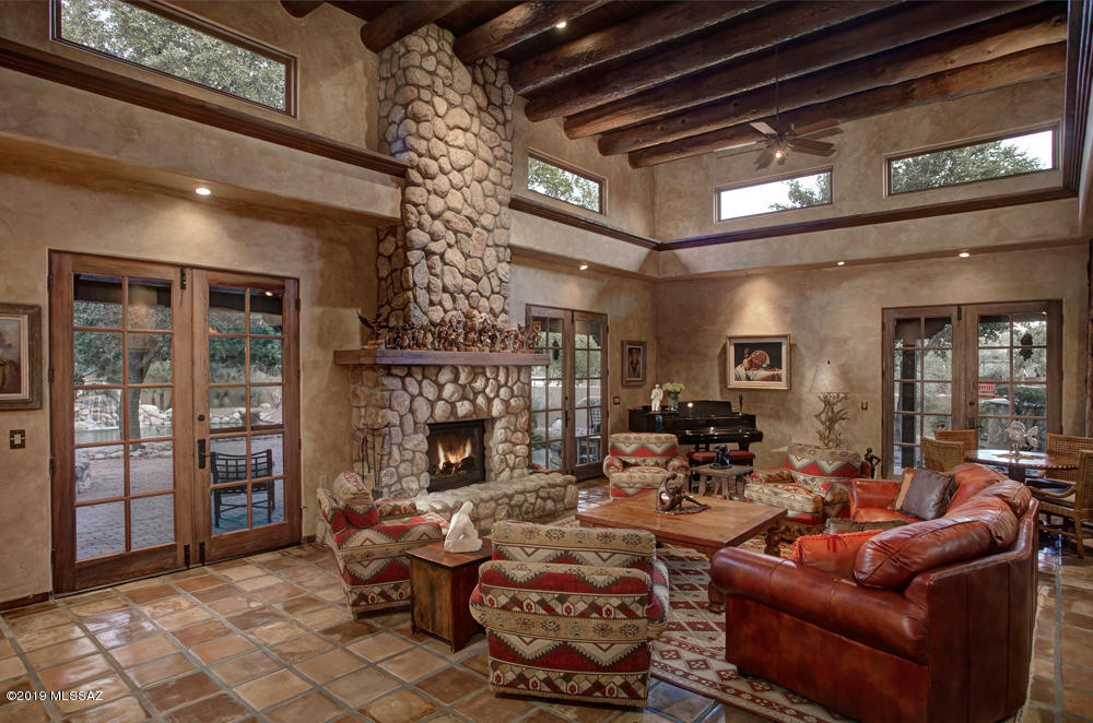 This spectacular Gentleman's ranch is nestled on 3.6 acres in sought after La Cienega. The one-of-a-kind custom Santa Fe offers unparalleled quality & detail. Highlights include gated courtyard entry, grand foyer, soaring beamed ceilings, Saltillo tile & wood planked flooring, solid-wood doors & custom faux paint.    The spacious great room features  high beamed & planked ceiling,   rustic stone fireplace, clerestory windows & 3 French doors leading to an expansive wraparound covered patios. The fabulous gourmet island kitchen provides top-of-the-line appliances, granite countertops, a farmer's sink, a walk-in pantry & a charming kiva fireplace. The master suite offers cozy fireplace & luxurious bathroom with dual walk-in closets, dual vanities, spa tub & walk-in shower. The gracious master suite offers a cozy fireplace, a built-in entertainment area, a sitting room with patio access, and a luxurious bathroom complete with dual walk-in closets, dual vanities, spa tub and walk-in shower. Bedroom 3 and 4 both include and en-suite bathroom and are adjacent to the playroom/bonus room. Enjoy the beautiful and very private outdoor living areas including an outdoor kitchen, a sparkling pool with waterfall feature, a spa, a ramada, and mature lush vegetation. The property also includes a detached heated & cooled 660 sq. ft. artist's studio. Additional features include a 3-stall horse barn, a turnout area, a round pen, a fire pit area, city water & a private well, and easy access to the wash & river walk. Conveniently located close to shopping, restaurant & hiking trails.