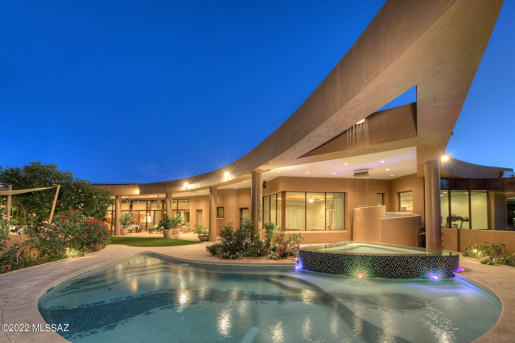 A stunning and architecturally significant contemporary home, designed by award-winning architect Ron Robinette with nods to Frank Lloyd Wright, I.M Pie and Frank Ghery as envisioned by the owners, located on a 1.1 Acre private lot in the prestigious upper double-gated communities of Pima Canyon Estates, is now available for discerning buyers. Interiors were designed by renowned interior designer Lori Carroll, featuring the finest of materials from around the world. This six-bedroom home offers 9,825 sq. ft. of living space, 676 sq. ft. covered entry, 1,877 sq. ft. of covered porches, a 4 car 1,428 sq. ft. garage and 13,806 sq. ft. under roof. Expansive curved glass walls of windows frame the Catalina Mountains as the desert changes seasons and time from a clear sunny day to the glorious sunsets and evenings filled with stars seemingly close enough to touch. The structure illuminates the breathtaking views of the Pima Canyon Mountains in harmony and at peace with nature. 

The entry to the home is a delightful shade garden with gentle water feature, framed by red-ochre shaded polished metal facades that capture energy, movement and light as envisioned by the architect/sculptor Frank Gehry. A single glass pivot door elegantly invites visitors into the home, leading to the stunning living room with soaring ceilings and and a fabulous sweeping arc of floor-to-ceiling glass windows and doors leading to the extensive outdoor patios, gardens, pool, and negative edge spa under an arch leading to a vanishing point as used by I.M. Pei. The gardens  and "outdoor rooms" formed by the covered patios flow into an outdoor heated and cooled catering kitchen for entertaining on a grand scale. Back inside, spaces flow into spaces with no clear delineation. Always a sense of movement in the space curvature with no static end point, as one moves into the kitchen area framed by a curved granite topped bar, with another island providing additional seating. The kitchen provides multiple work and storage spaces, with appliances including a pizza oven, built-in wok,  Thermidor  6 Burner + griddle cooktop, Gagganau wall ovens, separate Sub-Zero Refrigerator and freezer, and stunning cabinetry by Snaidero. An adjacent butler's pantry has a glass-front beverage refrigerator, Miele laundry facilities and lighted cabinetry storage. The kitchen flows into another sitting area with a built-in desk and casual dining option, all accessing the lovely gardens and fun play structure in the outdoors. The orthogonal but "circular feeling" dining "room" is a continuation of the living area and yet still its own space. 

There are extensive built-ins and coffered ceilings throughout the home. Materials for the home have been sourced from around the world and are both unique and sumptuous. A broad hallway curves into bedrooms and moves gracefully to another vanishing point. The Owners' Suite is exquisite and generous, with elegant bath areas and stunningly detailed closets for two. Broad windows look over the negative edge spa and up to the mountains. Adjacent is a gym space accented by large windows and rubberized flooring. The three childrens' rooms are spacious, with one-of-a-kind baths utilizing Italian tiles, and a large playroom connecting two of these bedrooms. The sumptuous media room, on two levels, enjoys silk upholstered walls and a raw silk curtain over the screen. A salon/massage room is separated from the curving hallway by floor-to-ceilings frosted glass walls. Broad stairs lead to a lower level with another bedroom or activity area, and a long dressing area with multiple luxuriously enclosed closets and a hidden shoe vault to make a Princess proud. Even the garage is elegant, with handsome granite counters, and extensive cabinetry. 

As beautiful as the home is, it is also an engineering success story. The lot was raised almost 16 feet and large industrial metal pipes were placed under the home to allow seamless flow of water from surrounding areas so the natural habitat was preserved. An addition built in 2010 utilized a foundation of a curved post-tension concrete structure that allows for elasticity and less delamination of the concrete. 

Built with love and great attention to detail, this very custom home evidences character and attitude as well as a glorious space to live, play, entertain and work. It has been featured in multiple magazines. Please call for your private showing.