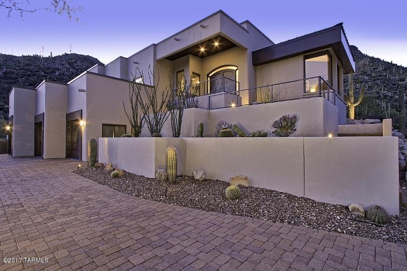 Striking Ultra Contemporary sits nestled against the Tortolitas in the picturesque, guard gated community of Canyon Pass at Dove Mountain. Dramatic arched iron & glass double entry doors welcome you while a private rear oasis boasts a pool w/dramatic rock waterfall, inground spa, putting green, grill station, linear fireplace and remote sunshades. Complemented by Natural Stone and Wood flooring, the main level boasts an impressive Great Room with Formal Dining, state-of-the-art Kitchen featuring Wolf & Sub-Zero appliances, plus Dual Master Suites (one w/adjacent Office). Lower level accessed by elevator hosts a 3-car garage, 600+ bottle Wine Cellar and  Media Room. Whole house wired for A/V. Spectacular Canyon views are afforded from most every room of this luxurious mountainside retreat!