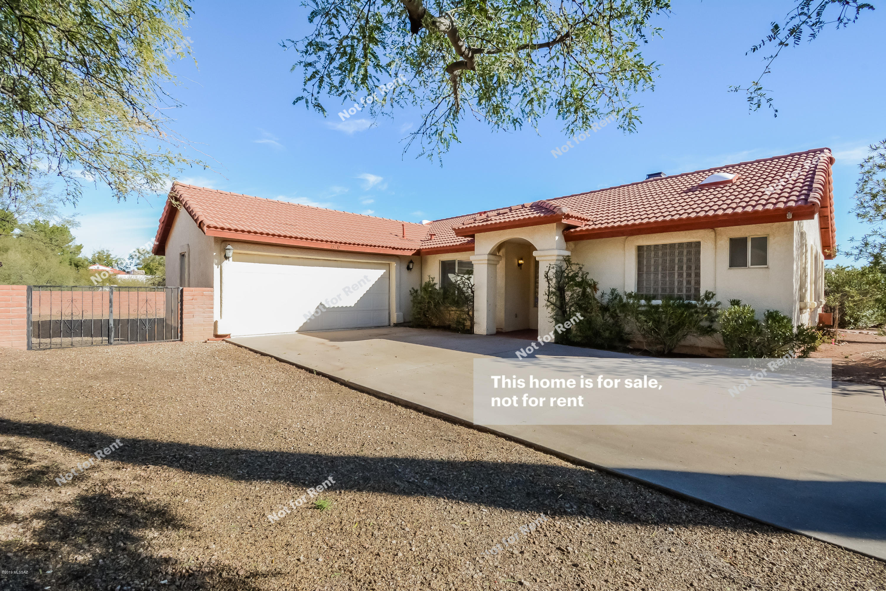 This Sahuarita one-story home offers an in-ground pool, tile flooring, a gas fireplace, a covered back patio, stainless steel appliances, granite kitchen countertops, and a two-car garage.