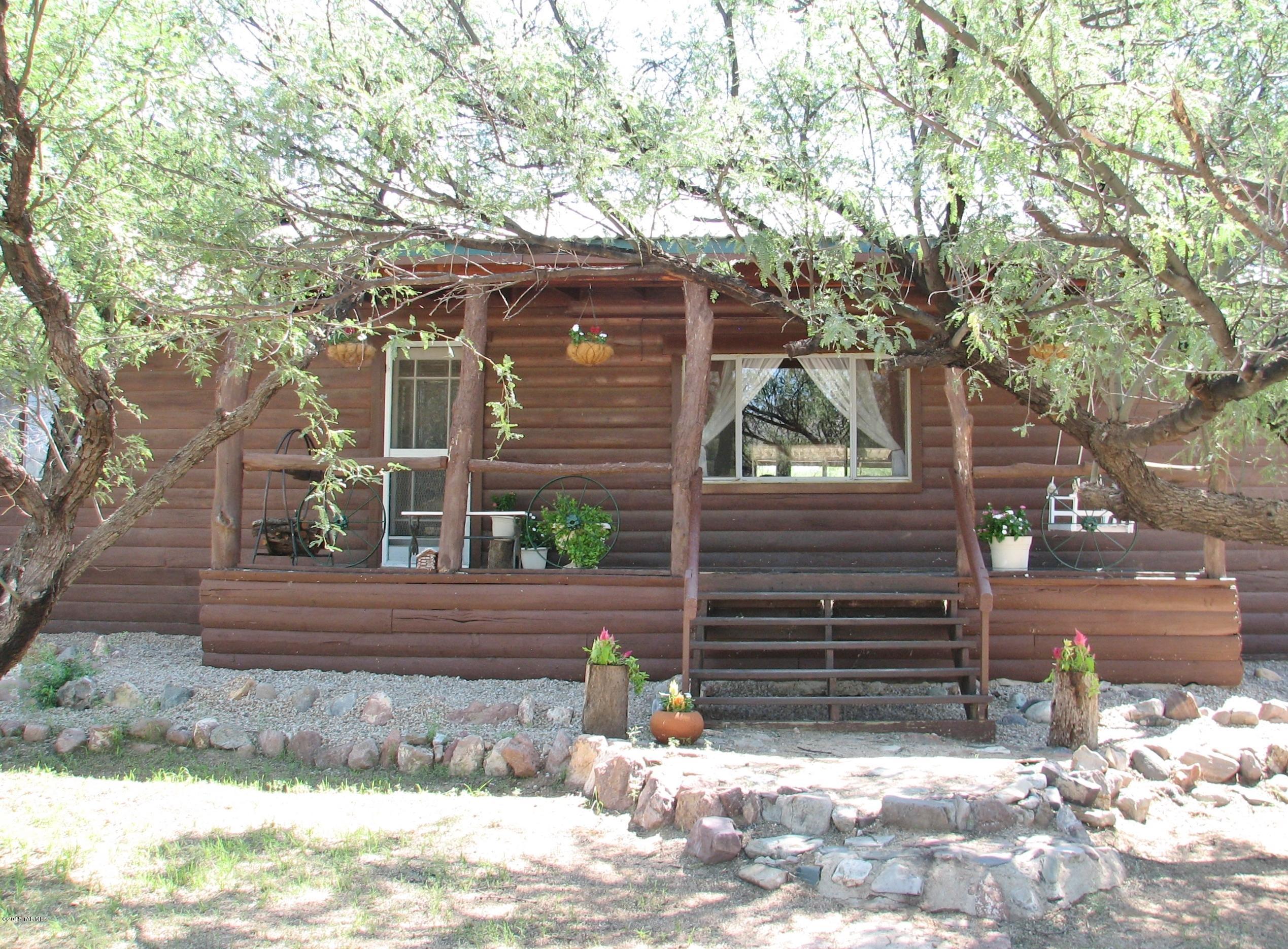 Wonderful Log House with new Metal Roof, new furnace, new dormer windows in attic/loft! Spacious living room with wood stove, sunken family room that leads to the solarium. Country kitchen has loads of cabinets.  Attic/loft has pull down stairs and new cheerful dormer windows.  On paved Cascabel Road, Private well, fully fenced with pasture, rustic 20x26 workshop, koi pond, views, mature landscaping!  Covered front and rear porches.  Borders STATE land!  Just too cute to pass up !!