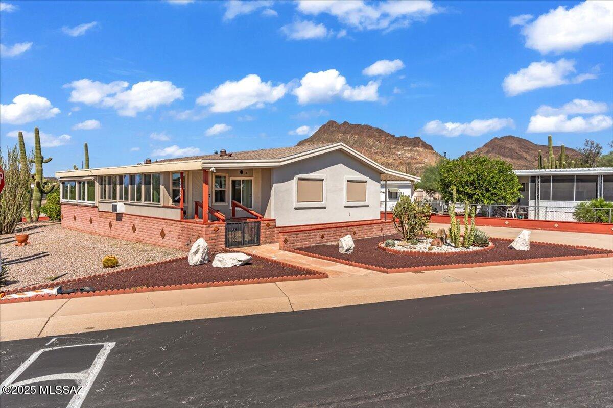 On a desirable corner lot, this charming home offers mountain views and a prime location directly across form the HOA facilities. Updated interior featuring newer windows that fill the space with natural light. The kitchen boasts modern cabinets, the hall bathroom is equipped with a walk-in tub. The primary suite offers a nice size with a wall of cabinets for abundant storage. Enjoy Arizona living year-round in the two separate heated and cooled Arizona rooms, perfect for relaxing or entertaining. The low-maintenance stucco exterior and two sheds- large enough for a golf cart garage. The property is part of a community with unlimited free golf and an impressive list of amenities, including two pools, a spa, a workout facility, shuffleboard, pickleball, tennis courts and you own the land.