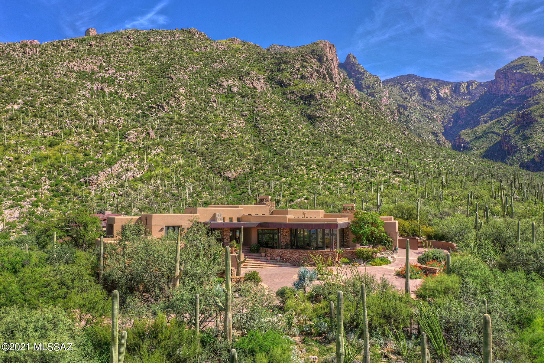 This spectacular 7,200 sq. ft., all masonry stucco masterpiece by Jeff Willmeng Homes is nestled on one of the best view lots in arguably the finest luxury subdivision in Tucson. Located at the end of a cul-de-sac in guard-gated The Canyons at the top of Alvernon Way, this dramatic Frank Lloyd Wright/Craftsman-style Southwestern contemporary offers breathtaking unobstructed city and mountain views! The property backs up to the Coronado National Forest at Finger Rock Canyon. No details have been left to the imagination in this masterpiece! Highlights include a leaded-glass/Wright-inspired front door, soaring ceilings, walls of windows, and city or mountain views from every room! The grand living room features a dramatic floor-to-ceiling stacked-stone fireplace.