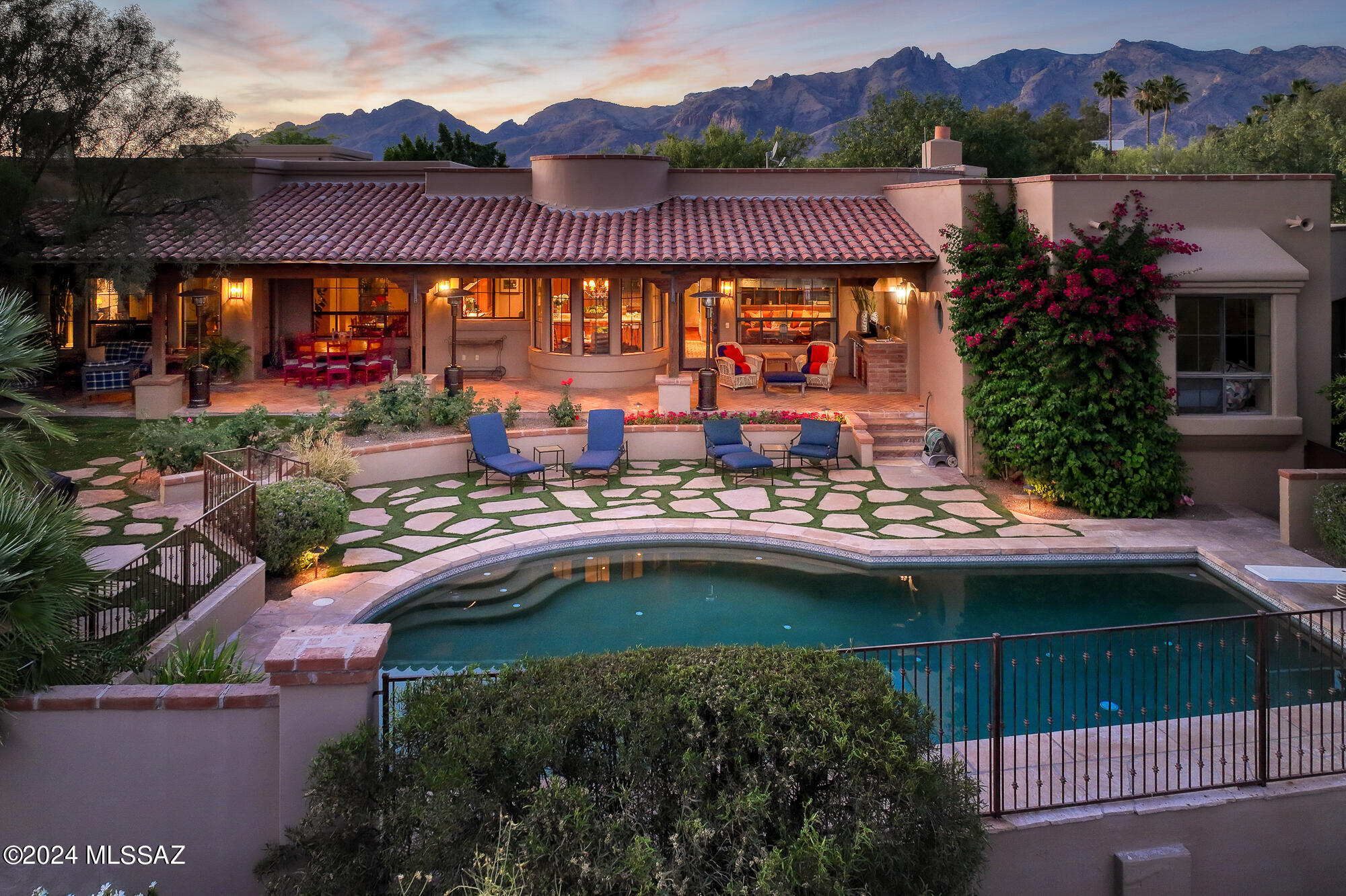 Quintessential Tucson home with a guest casita situated on an elevated homesite in the heart of the Old Foothills. Experience a private & secluded sanctuary-style retreat with expansive views of the city, iconic Tucson sunsets, & mountains in every direction without sacrificing proximity to the U of A, the Loop,, the best restaurants, shopping, &  more. This meticulously remodeled home reflects a unified vision executed to perfection with the assistance of acclaimed interior designer Linda Robinson. The result is a flawless masterpiece of curated materials that envelop you in livable luxury & understated sophistication. The shade of a canopy of mesquite trees produces an enchanting introduction & a romantic ambiance that sets this property apart...continued... Intentional architectural details, brick-capped smooth stucco, flagstone walkways, wood-lined red-tile porches, & distinctive windows come together to present a modernized version of a classic Tucson home. The split-level floor plan separates the main level of the house with a refined kitchen completed with a masterful combination of the finest materials, five en-suite bedrooms (including the separate guest casita), an office, a library & 2 powder rooms from the lower level designed purely for recreation & entertainment. The lower level includes a game/media room with a wet bar & bathroom, a fully equipped workout room, an oversized storage closet & a covered patio that leads to the newly finished & lit pickleball/basketball court. The indoor & outdoor living spaces flow seamlessly with a series of verandas & dynamic spaces that encourage stepping outside to take in the views & the beauty of the natural surroundings at any time of day. In the foreground of panoramic views of the city & mountains surrounding the valley is a resort-style backyard designed for small or large-scale entertaining with an extensive covered patio, outdoor kitchen, flourishing landscape, a pebble-tec pool, & an outdoor fireplace for guests to gather on a cool winter night. This prime foothills location offers District #16 schools.  Convenient to world-class golf resorts & country clubs, hiking trails in the Catalina Mountains, the Loop- a 133-mile connected bike path, the St. Phillip's Plaza/weekly farmers markets, Trader Joe's, yoga & CrossFit studios, and much more. 
Main level:
On the main floor: The foyer sets the tone with a dramatically high ceiling adorned with hand-hewn beams, walls finished in Venetian plaster & hardwood floors that carry throughout the home. Just off the entry is a beautifully finished powder room with Santa Barbara-style tile wainscoting & refined custom finishes & two large en-suite bedrooms with walk-in closets. Behind the beautiful imported double doors off the entry, you will discover a library & reading room, another ensuite bedroom & stairs down to the lower level. The exquisite formal living room houses a grand piano & stone-covered fireplace flanked by built-in shelving with beautiful wooden doors. A vaulted barrel ceiling distinguishes the adjacent formal dining room, designed for hosting friends & family for any occasion. The exceptional kitchen is a light-filled timeless work of art that opens to a cozy family room with a fireplace & a breakfast nook perfect for informal dining. The kitchen is completed with the finest materials, including imported brick flooring, Sub-Zero & Wolf appliances, hand-crafted cabinetry, high-quality hardware, a one-of-a-kind hood vent, & a farm sink overlooking the lush backyard, pool & city views. The large center island that anchors the space has a honed quartz countertop, a prep sink, a wine refrigerator & beverage drawers. A custom wet bar area within the kitchen provides additional storage for glassware & space for guests to help themselves to drinks. A second, nearby powder room is conveniently placed for guests The kitchen/family room area effortlessly flows to the herringbone pattern brick patio. An outdoor kitchen area with a built-in BBQ, sink & refrigerator is just steps from the kitchen. The en-suite guest casita with a private entrance is nearby. The impressive covered patio extends the length of the back of the house (1000 sf of covered patio), providing plenty of space for outdoor living, dining &  large-scale entertaining. The resort-like backyard boasts a pebble-tec pool surrounded by flagstone & grass, a kiva fireplace with plenty of room for seating, a large grassy area, lush, mature landscaping & sensational views of the twinkling city lights below.  The master suite wing offers supreme privacy with a separate, private hallway leading to an office with handcrafted built-in shelves & cabinets & the luxurious master bedroom with a fireplace, a large private veranda & magnificent views. The spacious master bathroom has it all: a large window that captures the desert & valley views & streams in abundant natural light, dual vanities, a soaking tub, a separate shower & a big walk-in closet. The spacious, light & bright laundry room with a sink has abundant cabinets & counter space. The oversized 3-car garage with custom metal doors has two large storage closets & a door to the backyard & guest casita, allowing guests to privately access the casita when parking in the garage. 

Lower Level:
Designed purely for recreation & entertainment, the lower level of the home begins with a large open room with high, wood-beamed ceilings, a powder room & a wet bar with a beverage & wine refrigerator. The game room area is large enough for a pool table & the media room with custom wood built-ins has room for plenty of seating. A separate, fully equipped exercise room is the perfect place to get in a full workout at home. The oversized storage closet on the lower level provides ample space for all of your holiday decorations, seasonal clothing, &  more.  The interior space transitions seamlessly to the exterior space with a covered patio perfect for enjoying a meal or watching a pickleball match on the newly finished, lit court. Host a pickleball tournament or shoot hoops day or night. A flagstone terrace above the pickleball court with a second built-in BBQ & a gas fire feature is ideally positioned for sunset & mountain views. Stairs from the terrace connect to the main level of the home. 
In the area: 
The Loop: Tucsons 133-mile connected bike path
Trader Joe's
Whole Foods
Distance to Tucson Airport: 25 minutes
Distance to the University of Arizona: 12 minutes
Distance to downtown Tucson: 15 minutes

La Paloma Country Club: 27 holes of golf, tennis, pickleball, lap pool, kids club, swim team, work-out facilities, excellent restaurants, resort pool & a plethora of activities and seasonal events.

Skyline Country Club: golf, tennis, lap pool, workout facilities, excellent restaurant, seasonal events.

La Encantada Mall: Shopping - Crate & Barrel, Pottery Barn, West Elm, Williams Sonoma, Lulu Lemon, Athleta, Vuori, Tiffany's, Blue Mercury, Kendra Scott, DryBar & much more
Restaurants & Grocery- A.J.'s Fine Foods, North Italia, Blanco, Firebirds, Ra Sushi Bar, True Food & Frost Gelato.

St. Phillip's Plaza: Weekly farmers market, live music & more.
Restaurants- Ren Coffeehouse & Bakery, Reforma Modern Mexican, Proof Pizza & Pasta, Pure Love Juice, Union Public House & Arizona Wine Collective.
Health & Fitness- F45 Training, Yoga Pod, Bodyworks Pilates & Revolve Cycling
Shops- W Boutique, Alfonso Oils, & Shop Klio

Joesler Village:
Restaurants- PF Changs, Sullivan's, Zin Burger, & Seis Kitchen

Campbell Plaza: 
Restaurants- Dough Bird & Flower Child

Nearby Hiking Trails:
Pima Canyon Trail
Campbell Avenue Trail
Finger Rock Trail
Ventana Canyon Trail 
Sabino Canyon Recreation Center


Schools:
Located in Highly-Rated Catalina Foothills District #16 schools. Some area Charter Schools include Basis, Lehman Academy of Excellence, Khalsa Montessori School, & the International School of Tucson . Some area private schools include Pusch Ridge Christian Academy K-12, Castlehill Country Day School Pre-K to 5th, the Waldorf School newborn-8, St. Cyril's K-8, Salpointe Catholic HS, the Gregory School 5-12.