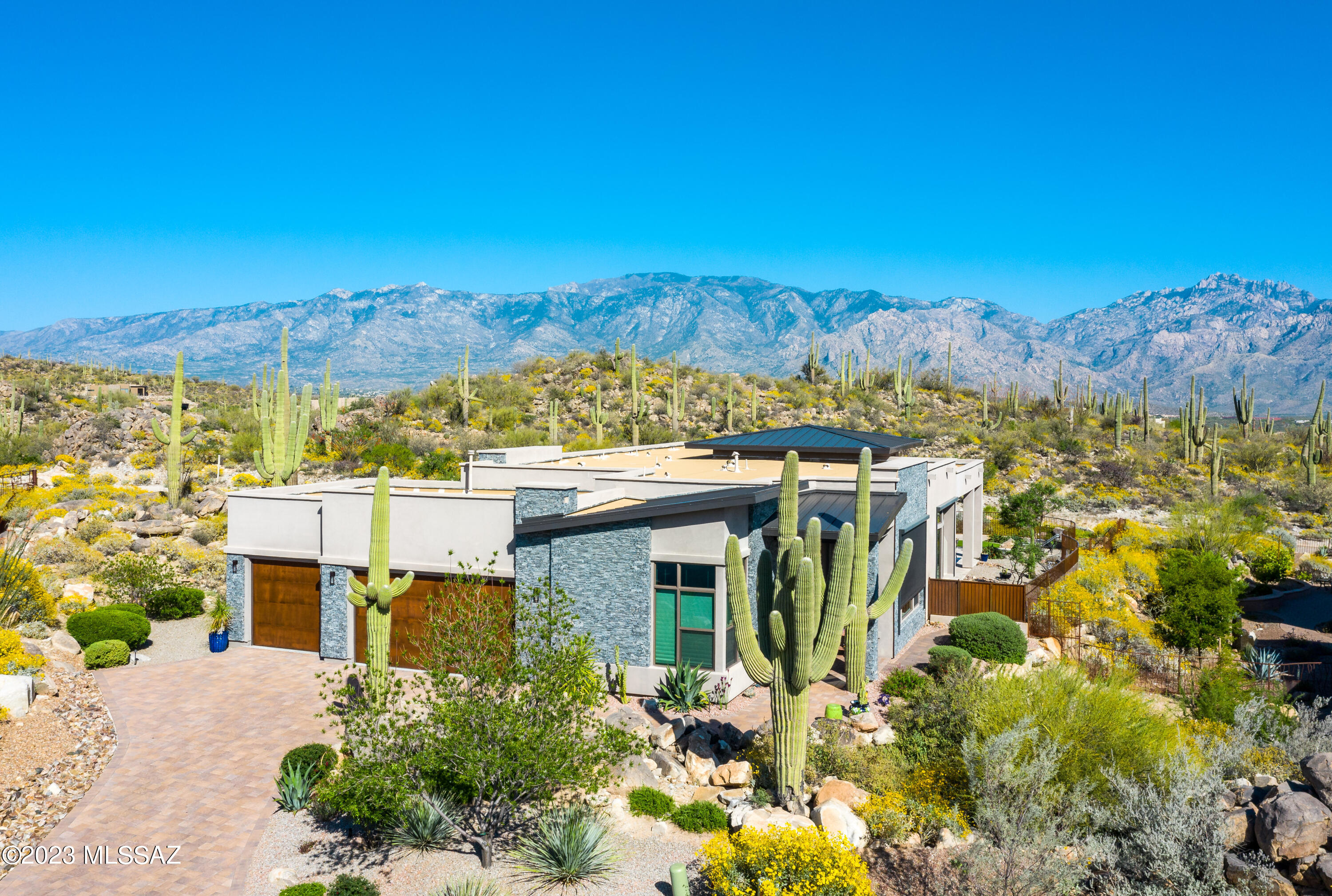 Captivating views of the Catalinas and outcroppings. Gorgeous contemporary with open great room in guard-gated Stone Canyon's Boulder Vista community. High ceilings and windows bring the outside in to almost every room. Formal entry, two guest suites, 3-car garage with epoxy floor. Luxury kitchen with walk-in pantry, handsome den/office, built-in bar, and attention to detail throughout. Private yard with covered L-shaped patio and rolling sun screens. The primary suite offers stunning mountain views, yet private, bath with large shower, dual vanities & spacious closet. Meticulously maintained for year-round or seasonal enjoyment.