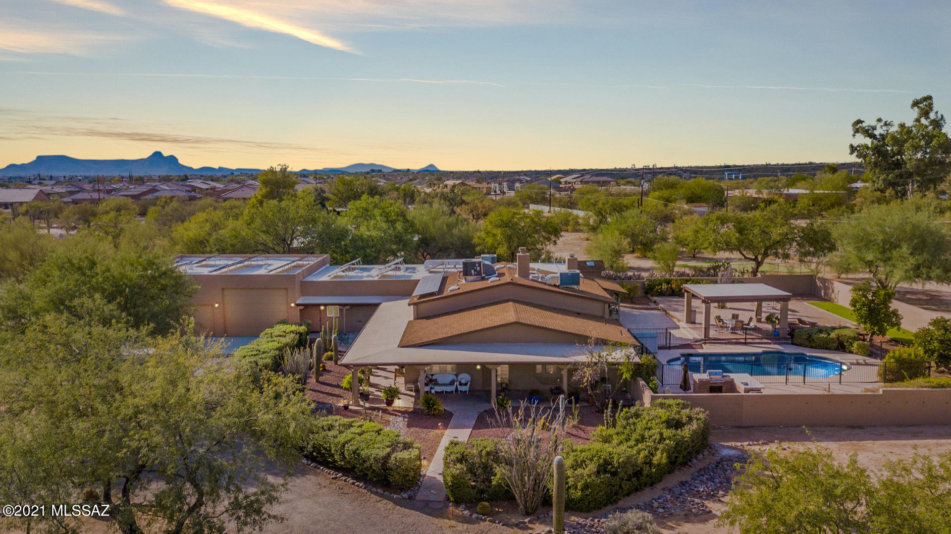 This meticulously maintained energy efficient solar home is versatile and inviting! It's perfect for entertaining  and enjoying life both inside and out. It is suited for blended and multi generational families with separate living spaces.There are large open spaces and cozy corners on this 1.3 acre horse property.  All outdoor spaces are well lit, easily maintained and on timed irrigation. There are fire pits outside north and south and great views of the mountains. The covered patio surrounds much of the home providing shade both inside and out. There's also a large covered ramada, bocce court, horseshoe pit, raised gardens for vegetables and herbs, along with mature fruit trees, an outdoor gas kitchen and a large fenced pool with a diving board for your outdoor pleasure. The inside of this home is open, spacious, and light.  All new luxury flooring throughout the home is warmer and softer than tile, easy to clean and beautiful to look at and gives this home a whole new updated flow and feel. Check out the features list in the documents tab for all the recent upgrades. The grand master bedroom and en-suite is luxurious. There is a romantic fireplace  and sitting area, built-in decorative shelves, patio access, & upscale spa-like en suite w/dual sinks. 5 generous sized bedrooms, ample closets, 5 pristine bathrooms, dedicated office space, 3 indoor fireplaces, and 3 different family rooms allows for everyone to have their own spaces and places. On top of it all there is an 1800 sq.ft. garage to store 2 cars, and an RV with an enclosed 24x14 work/storage space that has water and air conditioning.