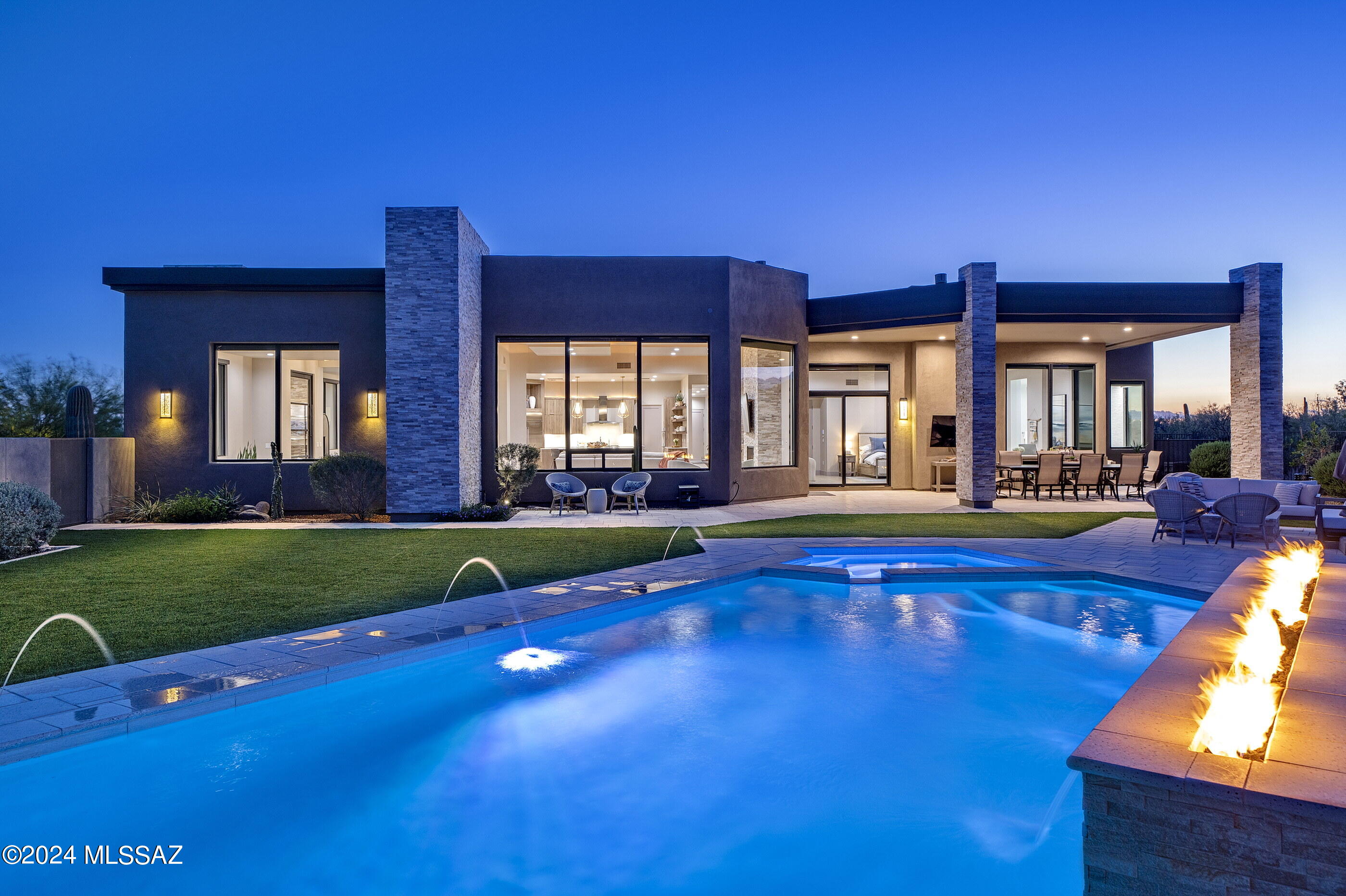 Located in the prestigious Pima Canyon Estates community, one of the finest private communities in the Southwest, and situated behind the secondary gates of Pima Gardens, sits a tranquil respite where one coexists harmoniously within the surroundings. The home's orientation offers soft natural light that filters into the great room through glass façades, with unobstructed Catalina Mountain and Pima Canyon views that stretch out over the surrounding desert landscapes. Entering the great room from the large glass front entry, one is immediately immersed within the dramatic mountain views while overlooking the pool and spa, providing a cinematic experience. Throughout the home, programmatic needs flow between indoor and outdoor living spaces that heighten the interior's sense of scale by extending the views outward.

The kitchen design features clean lines and a contemporary aesthetic, seamlessly blending into the surrounding architecture. Countertops offer a soothing natural stone finish, providing ample task space and adding to the kitchen's contemporary feel. Custom millwork, strategically placed for optimal functionality and ergonomic use, is positioned to overlook the great room, fostering a sense of connectivity within the living space. Tile floors line the interior, threading the living spaces together, while providing material continuity to the overall design aesthetic.

The generous owner's suite is privately sequestered on the north end of the residence, featuring an oversized walk-in dressing closet and luxuriously finished primary bath, which includes a large soaking tub, walk-in shower, and floating dual vanities. The balance of three secondary ensuite bedrooms are sequestered on the west wing of this split bedroom floor plan, perfectly suited for family, or guests alike.

Floor to ceiling glass walls spill out onto a back covered veranda, connecting the refuge of the home with the exterior living spaces. The pool and spa with linear fire element act as the centerpiece of the backyard, drawing in the surrounding mountain ranges, with the ever-changing skyline reflecting off the water's surface. Every comfort is considered and detail meticulously crafted, the result being an environment that offers a sense of ease to enjoy both lifestyle and entertainment.