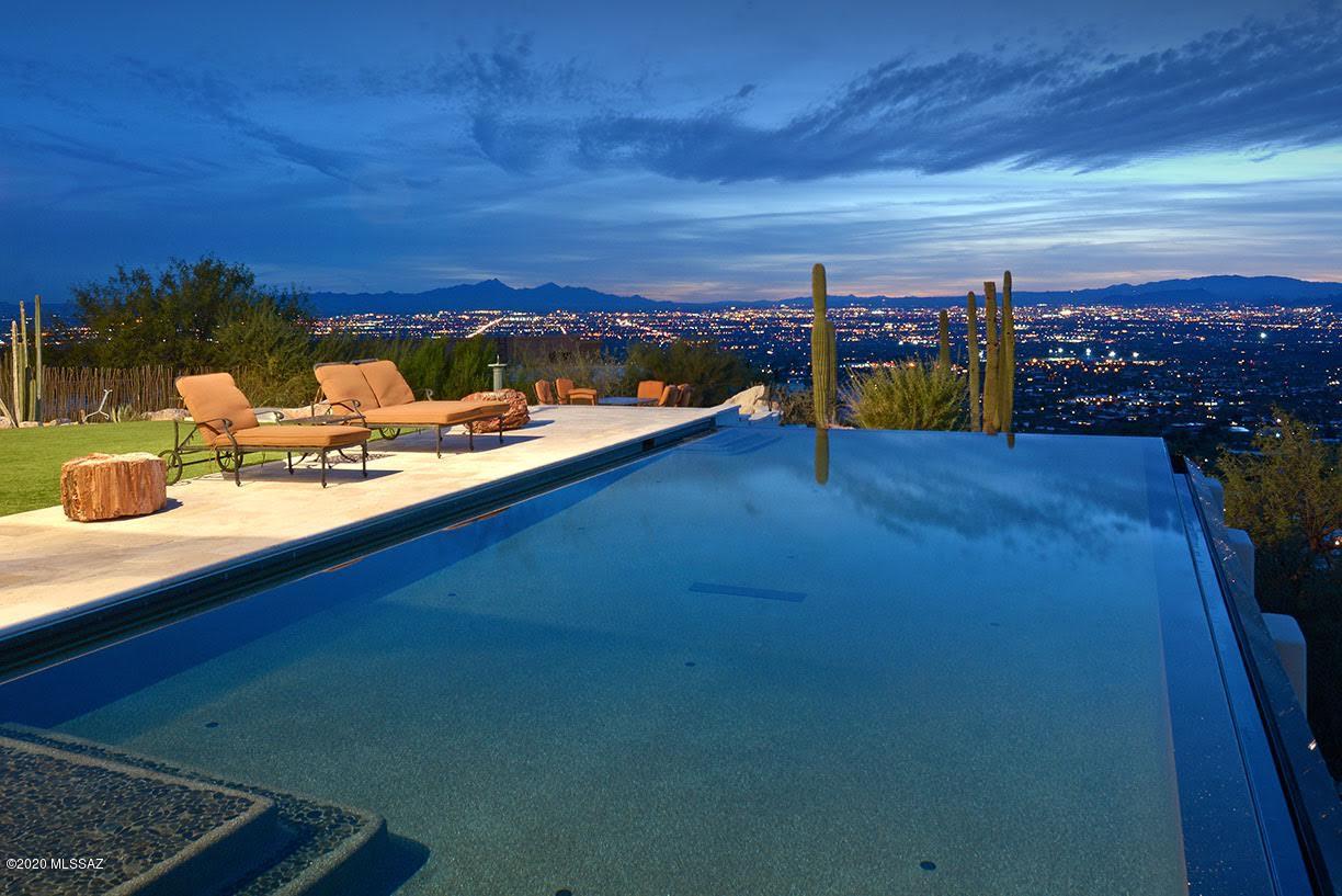 This magnificent estate with over three acres in the prestigious gated golfing community of Skyline Country Club is located on one of Tucson's highest, most premium lots with unsurpassed 360-degree views overlooking the city and four mountain ranges and touching the Coronado National Forest. It is a five-bedroom split plan home on one floor with a second master suite. The guest quarters, or entertainment room, with a bathroom and wine cellar are downstairs. The striking great room has ceiling length Pella windows, collapsible glass doors and spacious gourmet kitchen with commercial grade Thermador appliances. 3 gas bio fuel fireplaces. This home is plumbed for solar and insulated energy efficiency. Relax by negative edge Pebble Tec pool with cover that closes with the touch of a button.