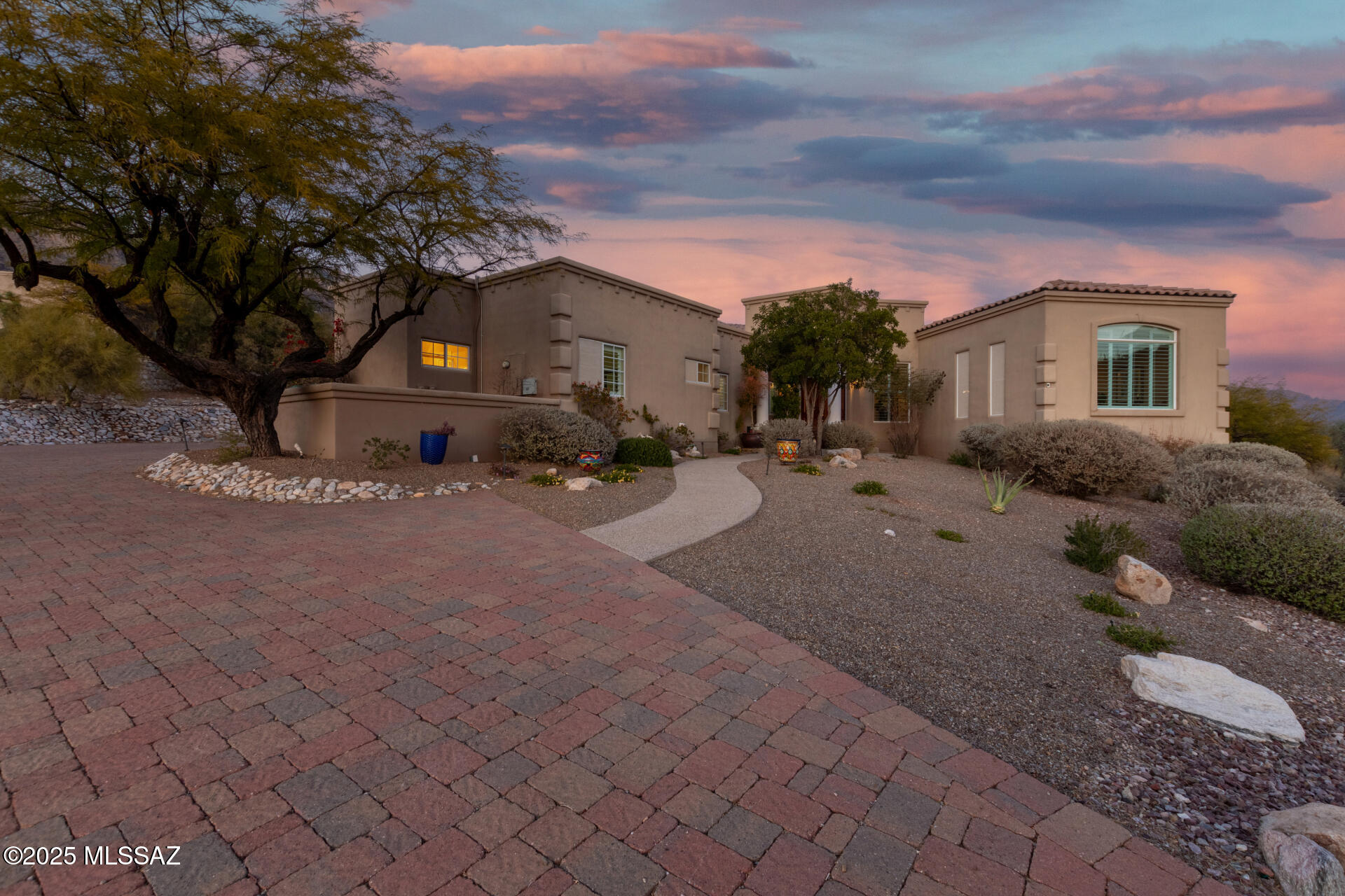 Experience breathtaking views in your private oasis at the base of the Catalina Mountains! This Alta Vista lot offers privacy, backs to a wash, & is on a cul-de-sac. The kitchen boasts a sub-zero fridge, 120-bottle wine cooler, 6-burner gas cooktop, double ovens w/ Wi-Fi, LED lighting, touch-activated faucets, a Reverse Osmosis water system and more. The family room features a gas/wood-burning fireplace & folding glass doors that blend indoor/outdoor living.The primary bath has Bluetooth medicine cabinets, 3 large closets, a rotating shoe rack, mother-of-pearl sinks, &  jetted tub w/ mountain views. Outdoors, enjoy 3 gas fireplaces, programmable pathway lighting, a sparkling pool, lagoon, & 8-person hot tub w/ waterfall, all heated & controlled by app. Wraparound patio for entertaining.