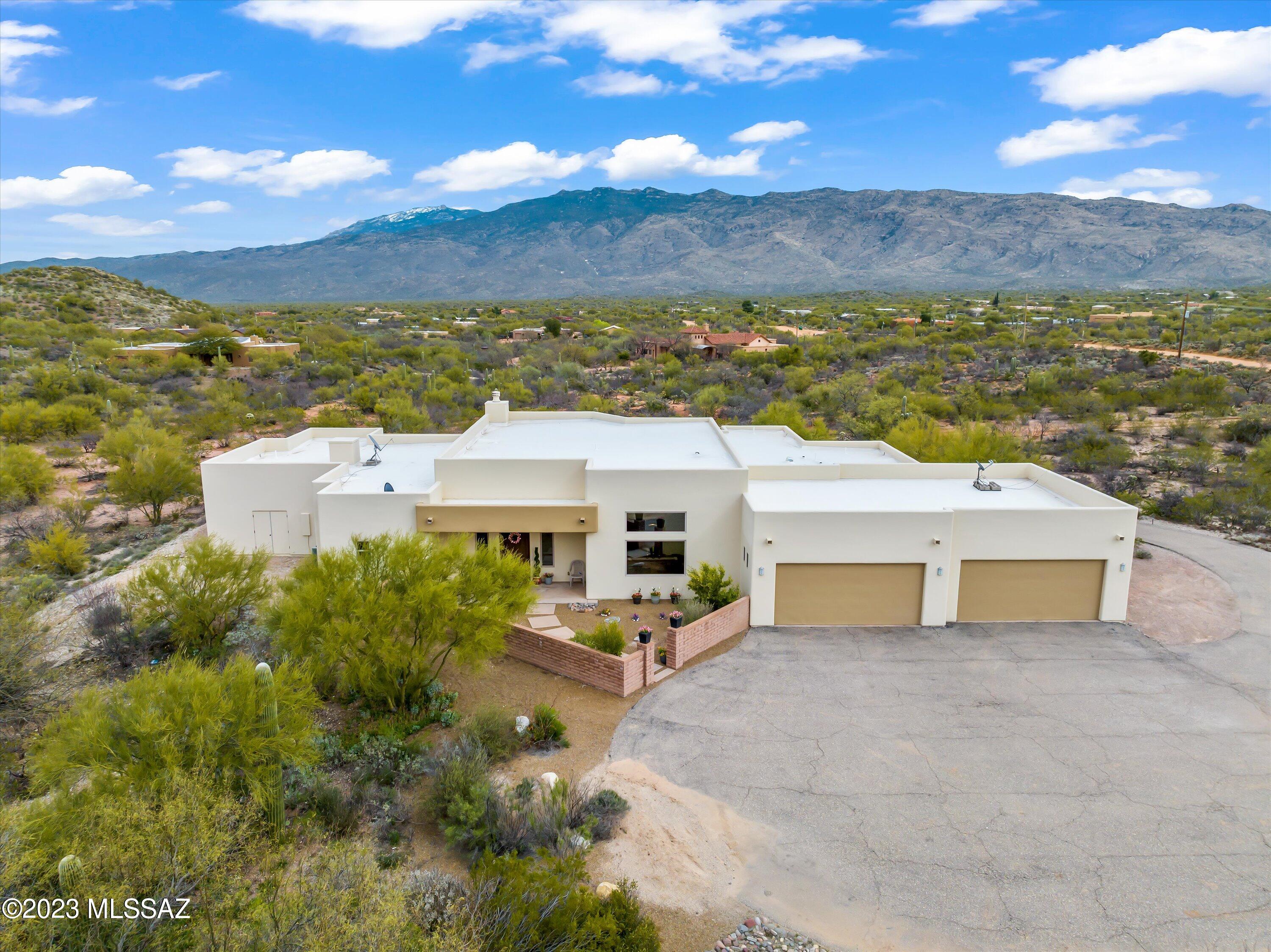 Beautiful Custom Contemporary sitting on a peaceful 3.73 acres w/stunning Rincon Mtn views. Flooring is Travertine & engineered hardwood. Oversize great room w/skylights, speakers, fireplace & wet bar complete w/wine & mini-fridge. Add in a private dining room & seating for 8 at the kitchen counter & you are truly entertaining. Step into the chef's kitchen w/granite counters, maple cabinets, soft-close drawers & large center island w/prep sink. Dual  refrigerators, Induction cooktop, dual convection ovens, new ice maker & generous pantry. Split plan offers a spacious primary suite w/side room, bath w/spa tub, dual sinks & views. Huge Laundry room has 3 year old W&D, handsink, cabinets & solar tubes. Secondary rooms have walk-in closets & very spacious. Oversize 1035 sq ft 4 car garage.