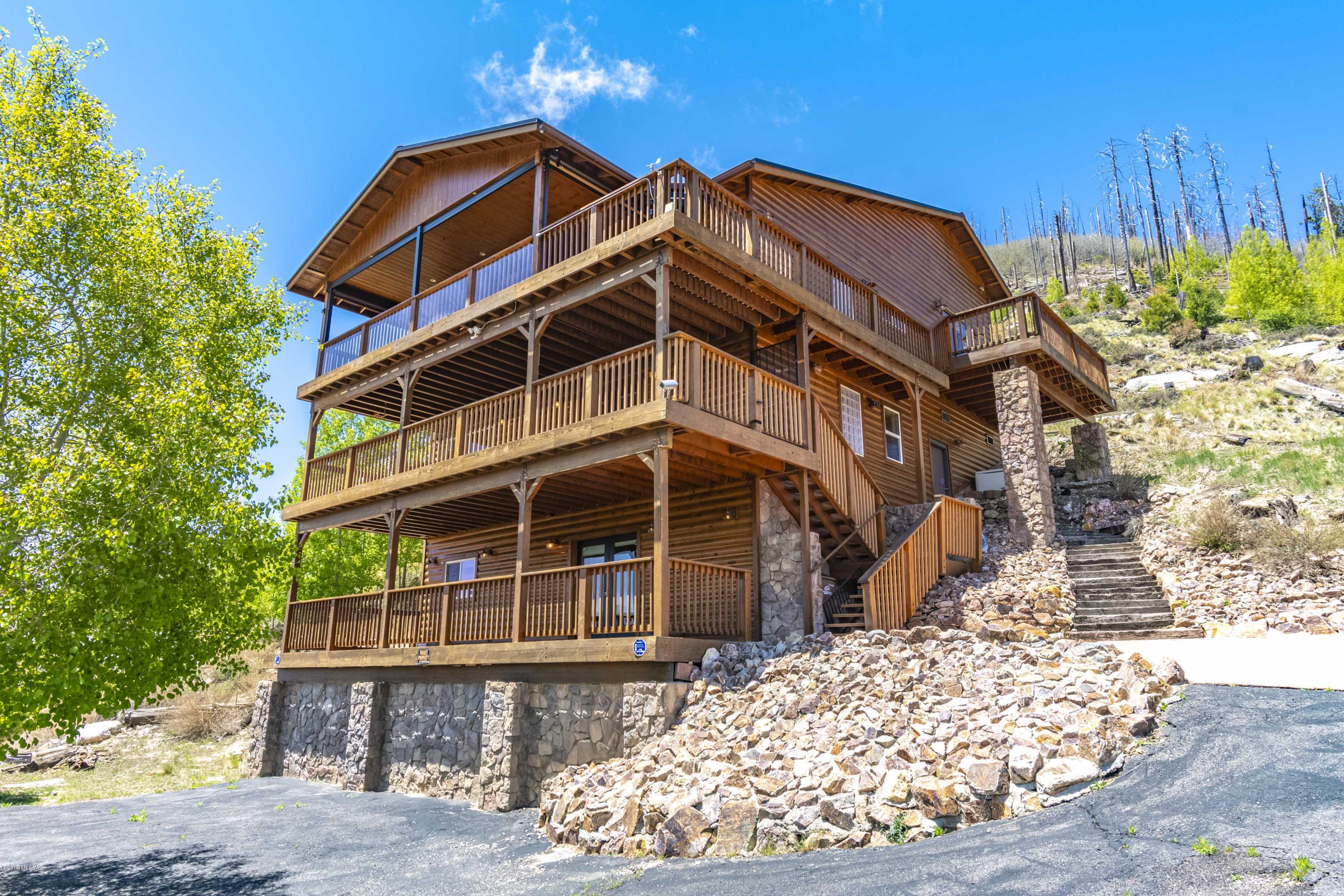 Stunning hillside home overlooking Summerhaven offers breathtaking views of the town and surrounding hills. This custom built beauty features 5br(3bedrooms plus a 4th loft bedroom and efficiency suite sleeping area) , 4ba with 3fireplaces inside (2gas one electric) and another fireplace on the 3rd deck outside. This decks also features retractable translucent sides so you can enjoy the outdoors year-'round.  The first floor is a guest efficiency suite with bar/kitchenette, electric FP, full bath and a large living area that doubles as a 5th bedroom. The second floor is a great room with a fireplace, office/BR and spiral staircase that leads to the third floor where the 3rd fireplace, living area, dining room and kitchen are located. There is a living room loft on the 3rd floor and steps to another level where the rest of the bedrooms can be found.  One is the spacious master bedroom featuring its outdoor deck that wraps around to the to the main deck, and a master bath with heated floors and a Jacuzzi tub.  The second bedroom features a loft for a additional, separate sleeping area.  All 3 floors have enormous patio decks.  There are stairs connecting all floors as well as an elevator.  There is a generator to provide power when electric service is disrupted.  This home is situated on 2 lots, giving you twice the frontage space and plenty of paved parking.  The road is county maintained, so you can enjoy your home even when the snow gets deep.  There is a recreational toy garage, workshop and loads of storage.  Home is pre-wired for phone, cable & Ethernet and includes intercom and security systems.
See specific details under documents tab.