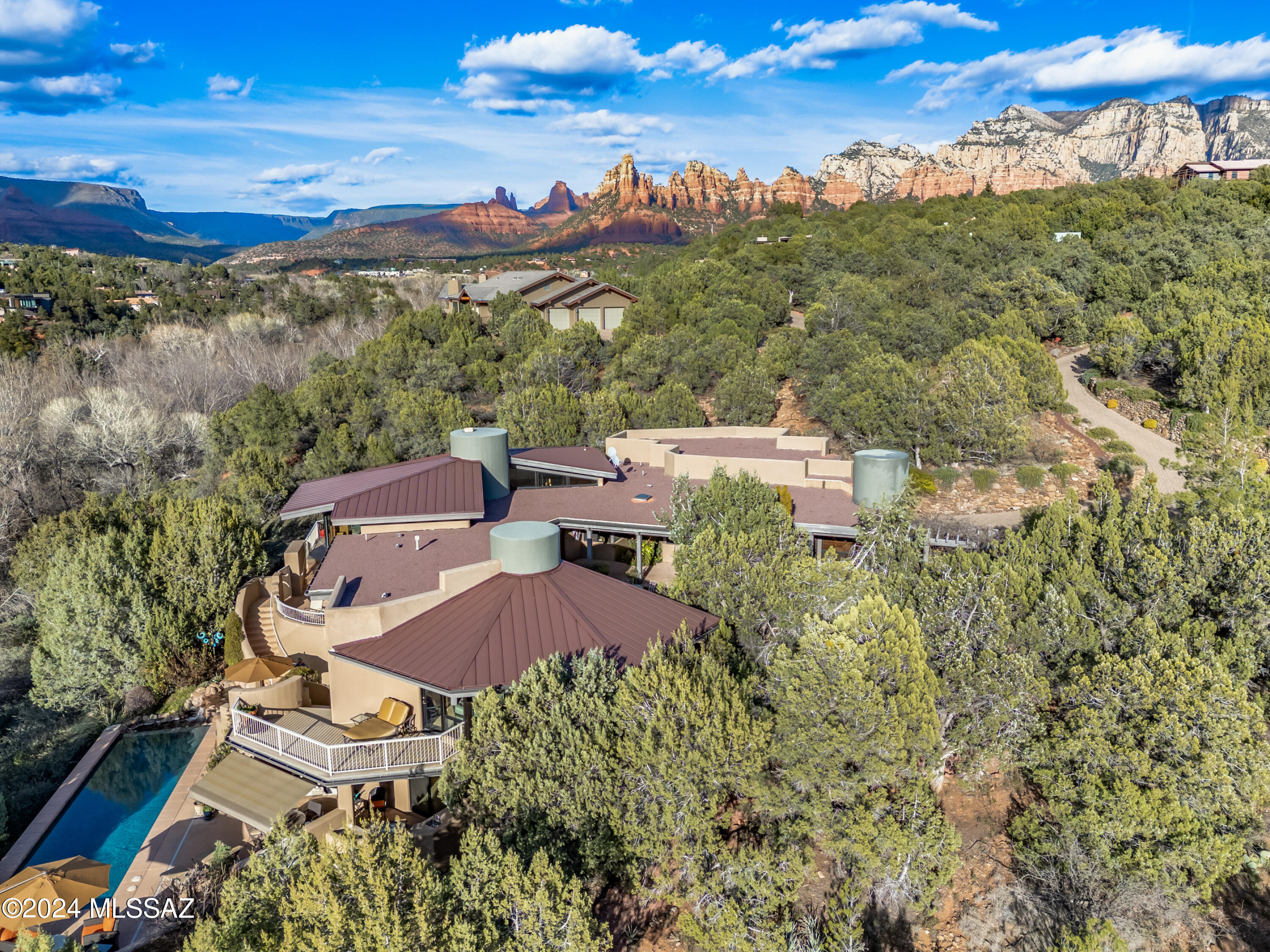 This stunning property in Sedona, Arizona, is a unique opportunity to own a piece of paradise in the highly desired Creek Mesa subdivision. The home was designed for a single owner who is an art enthusiast, to showcase their art and to enjoy the breathtaking views with privacy. Now, this hidden gem can be yours. The magic starts as you drive up from the private gate to your spacious paved driveway. You will see how the home blends into the natural flow of the mountain. As you lift your sight, you will be amazed by the majestic mountain views. As you walk into the bridge of greenery, you will hear the serene sound of running water in the delicately crafted courtyard. You will be greeted by a majestic architectural accent cylinder that serves as a centerpiece for art and warmth. The house offers a cathedral ceiling and floor-to-ceiling panoramic windows that not only provide natural light but also offer incredible views of Mountain Wilson. The split floor plan has an organic flow to enjoy the outdoors from every space in the home. The house offers many outdoor sitting areas, including a balcony and a fabulous spa just outside of the main bedroom. There is also a below-grade entertainment game room, a steam bathroom, and a wet bar, that opens to the outdoor kitchen and to the negative edge pool with a water feature. The pool is prepared to be used every day of the year, since it has a pool water heater heated by solar panels. It also has a convenient cover to use it at your convenience and keep it free from debris.

Your next home is adjacent to the community park and Oak Creek, meaning that only steps away from your home you can have a picnic with the multiple bbq pits and tables, as well as a sitting area to relax while listening to the running water. If you are a trail enthusiast, Creek Mesa Subdivision has a well-maintained trail that leads to the swimming hole along with scenic views. This subdivision is a gated community with luxury homes that offer mountain and red rock views. This house is a perfect blend of comfort, luxury, and nature.