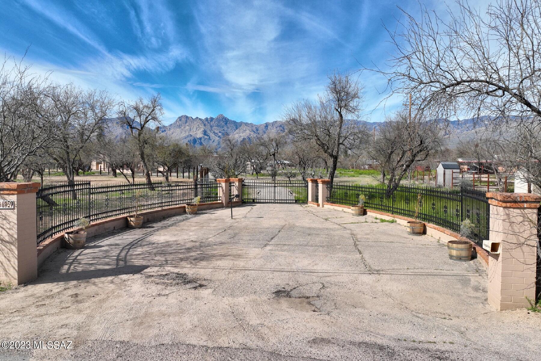 This 6.4 acre ranch is country living in the city.  Fabulous mountain views & only 500 feet from the trailhead leading to Tanque Verde Creek w/access to miles of trails for riding/hiking possibilities. 4,244 sqft home offers 3BD, 3BA, updated great room, gourmet kitchen, family/billiard room, office, & library + two stone FP's. Grand entry welcomes you w/high, wood-beamed ceilings that continue into the great room. 660 sqft guest house features a living/kit area & 1BD/BA. Private gated entrance, 2-car attached GAR, 2-car detached GAR + covered RV parking for all your vehicles/toys. Pebble-tec pool to enjoy the warm summer days. Water to the house/property provided by 1 private well + an add'l private well currently not being used. Entire property is completely fenced w/free range pastures. Property also has cross fencing so you can move your horses/animals safely to different parts of the property. Several outbuildings & b-ball court too. Take a drive down Woodland Rd, enjoy tall trees, green grass, animals roaming on lots of land...you'll see sheep, a bull, miniature donkeys, horses, goats and more. This exclusive neighborhood has it all.