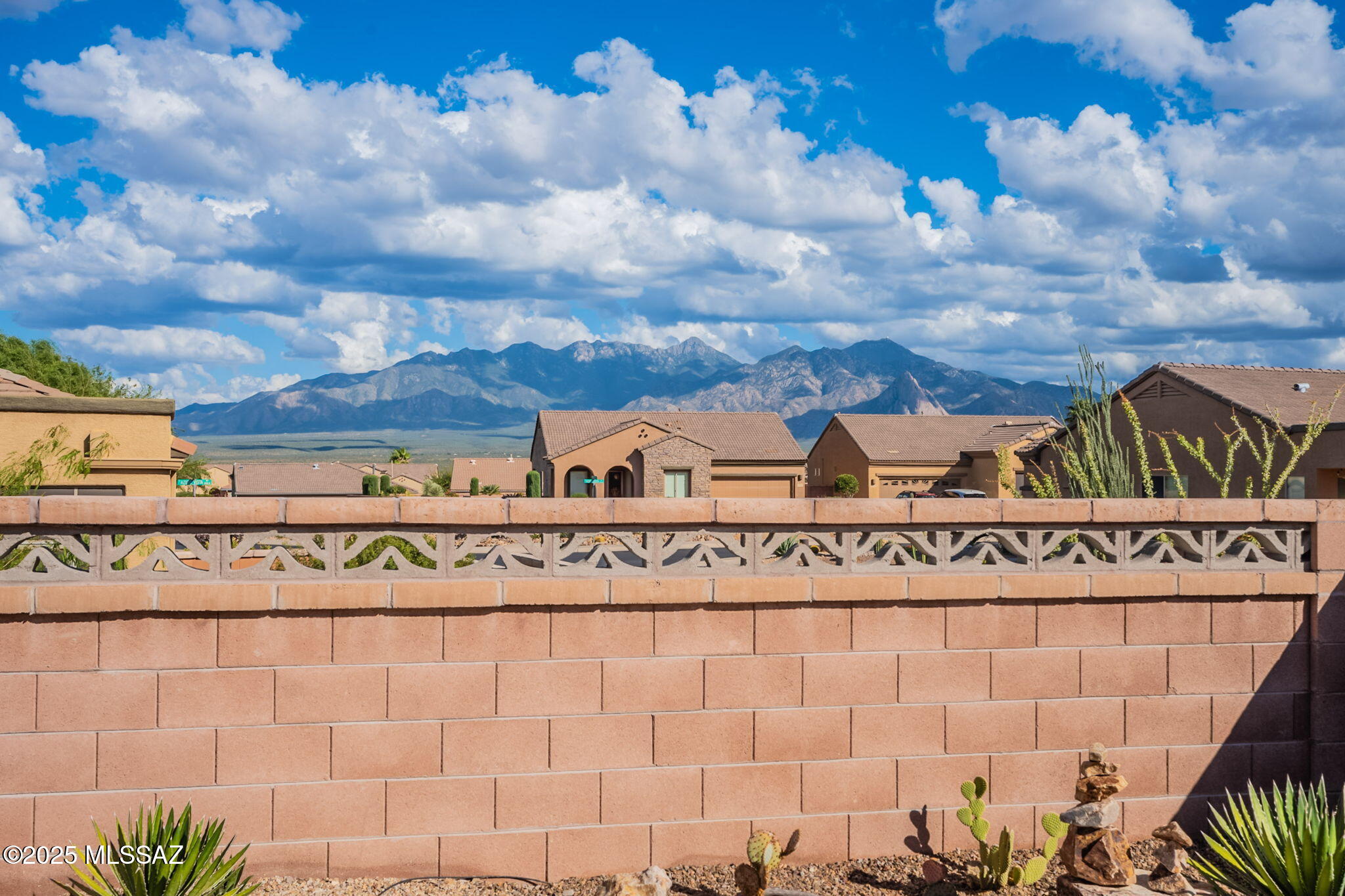 Escape to your own private desert sanctuary where contemporary design meets the  beauty of the beautiful Santa Rita Mountains!  This thoughtfully designed home offers the perfect blend of modern comfort and low-maintenance living, allowing you to focus on what truly matters - enjoying life under the endless desert sky. The heart of this home is the great room, where  windows frame spectacular mountain vistas like living artwork. Gather around the cozy fireplace as the sun sets behind the peaks.
The kitchen is the  perfect size for cooking and entertaining with a spacious dining room adjacent and a bar for overflow seating  Despite its intimate scale, this clever layout maximizes every square foot with two comfortable bedrooms plus a versatile den - perfect for guests, a media room, or a second office. Step outside to discover your personal resort-style retreat. The screened Arizona room becomes your favorite refuge during breezy desert evenings, and and a paved back patio is framed by mountain views and extends your outdoor living space.  This outdoor living area was created for al fresco dining and entertaining under the stars.  Spend your mornings watching the mountains awaken and your evenings under the stars, knowing that your low-maintenance sanctuary handles the details so you can focus on making memories. This home was designed for living, not maintaining, and  is your gateway to the desert lifestyle you've been dreaming of