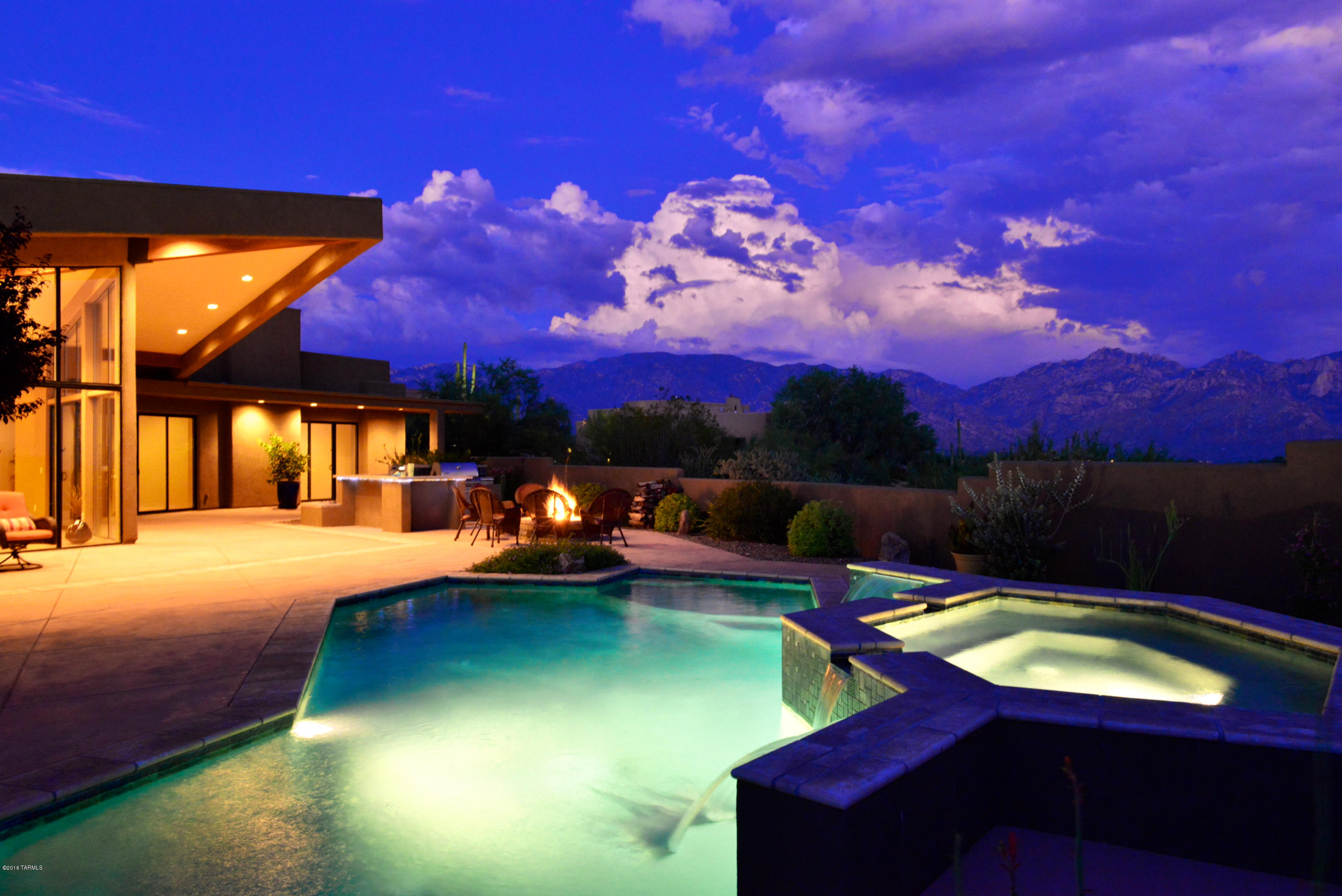 Striking contemporary architecture showcases open design with bold elements and flowing layout. Elevated setting in gated Honeybee Canyon provides sweeping views of Catalina Mtns, valley and distant city lights. Soaring ceilings & windows highlight the impressive styling and polished concrete flooring thru-out. Great Room, Den, Rec Room & 3BD/4BA in split layout. Chef's kitchen with spacious granite counters, gorgeous cabinetry and premium SS appliances (8-burner gas stove w/hood & 2 ovens plus built-in refrigerator and microwave). Pool & spa with spillways, built-in BBQ and multiple patio areas. Hillside location provides both privacy & stunning views for seasonal or annual AZ lifestyle! Located next to Phil Mickelson’s Stone Canyon Club. One Seller is licensed AZ REALTOR®.