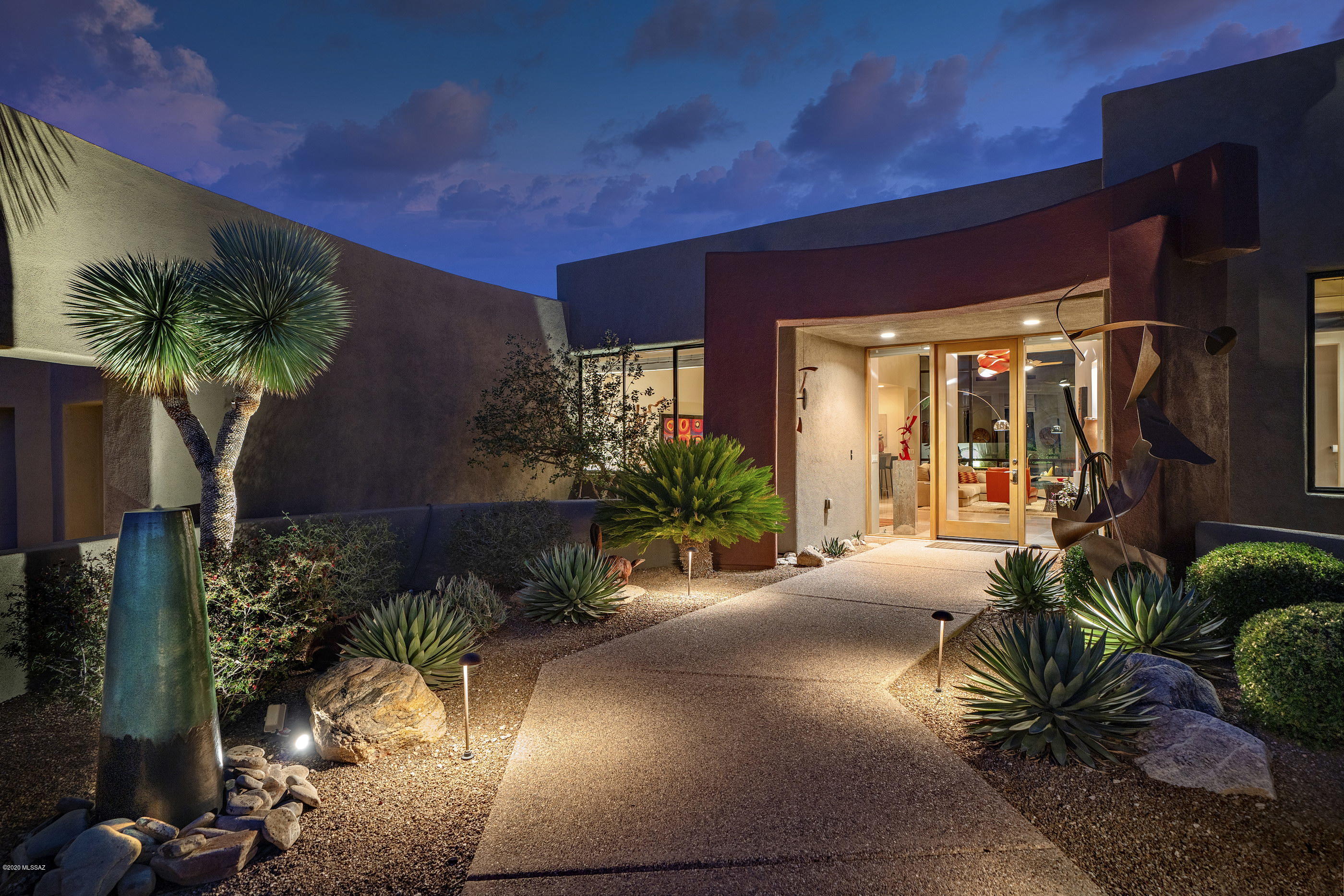 Gorgeous Popson built property is exceptional—the epitome of thoughtful design. Great room boasts a massive wall of windows that overlook the pool & showcase the mountains, floor to ceiling stacked stone fireplace & a wet bar.  Kitchen features a full suite of stainless-steel KitchenAid appliances, including a five-burner gas range, warming drawer & two full size dishwashers. Ultra-dramatic guest bath off the great room is a designer dream. The primary bedroom suite & a separate den (which has a closet & could be the fourth bedroom) occupy one side of the home, while the other wing features two bedrooms, both with private en suite baths & access to the outdoors. Reverse neg edge pool & outdoor kitchen. Natural stone floors throughout. Large 3 car garage has workshop space & storage room.